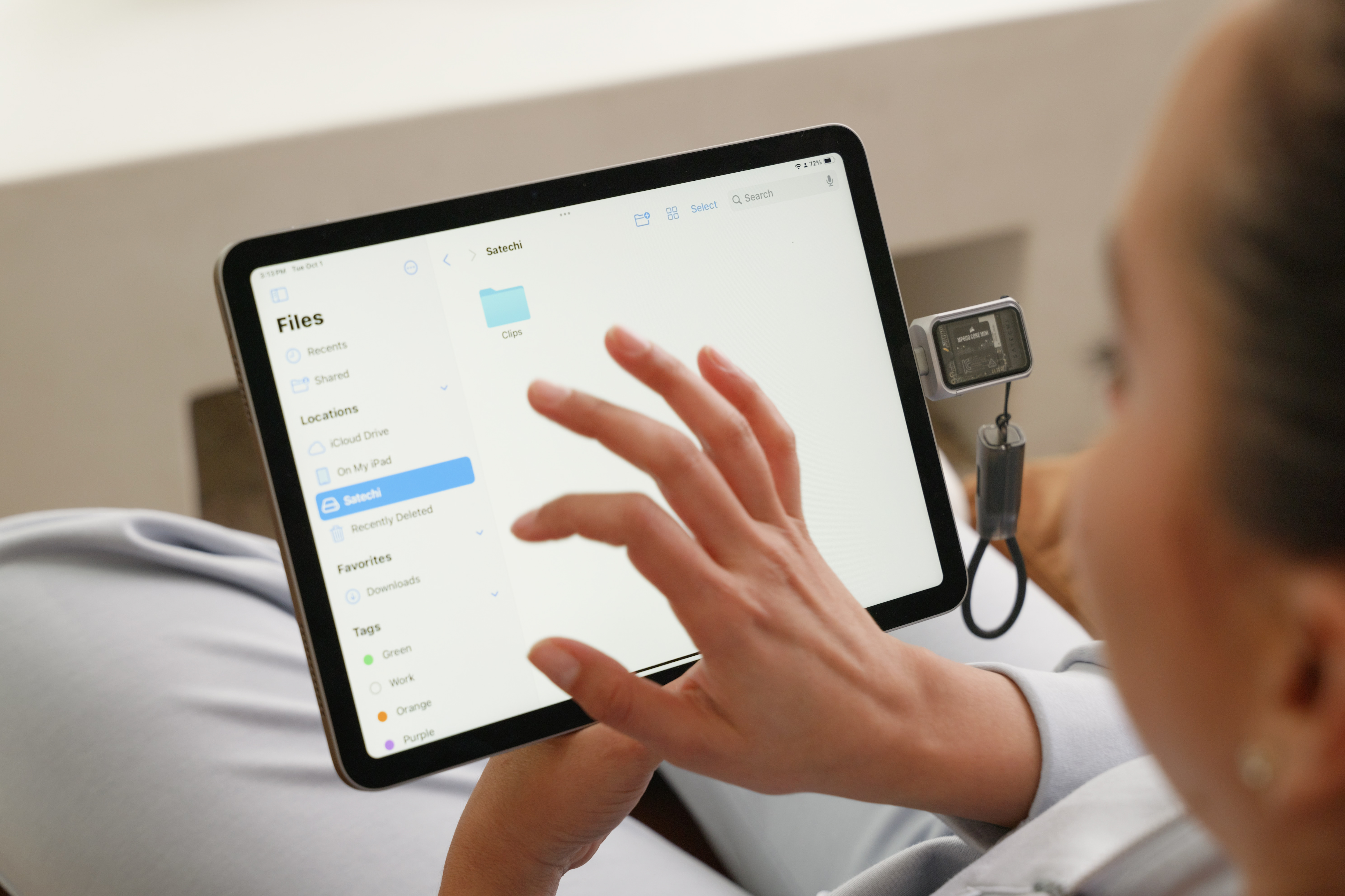 A person using a Satechi Mini NVMe SSD Enclosure to offload files onto their iPad.