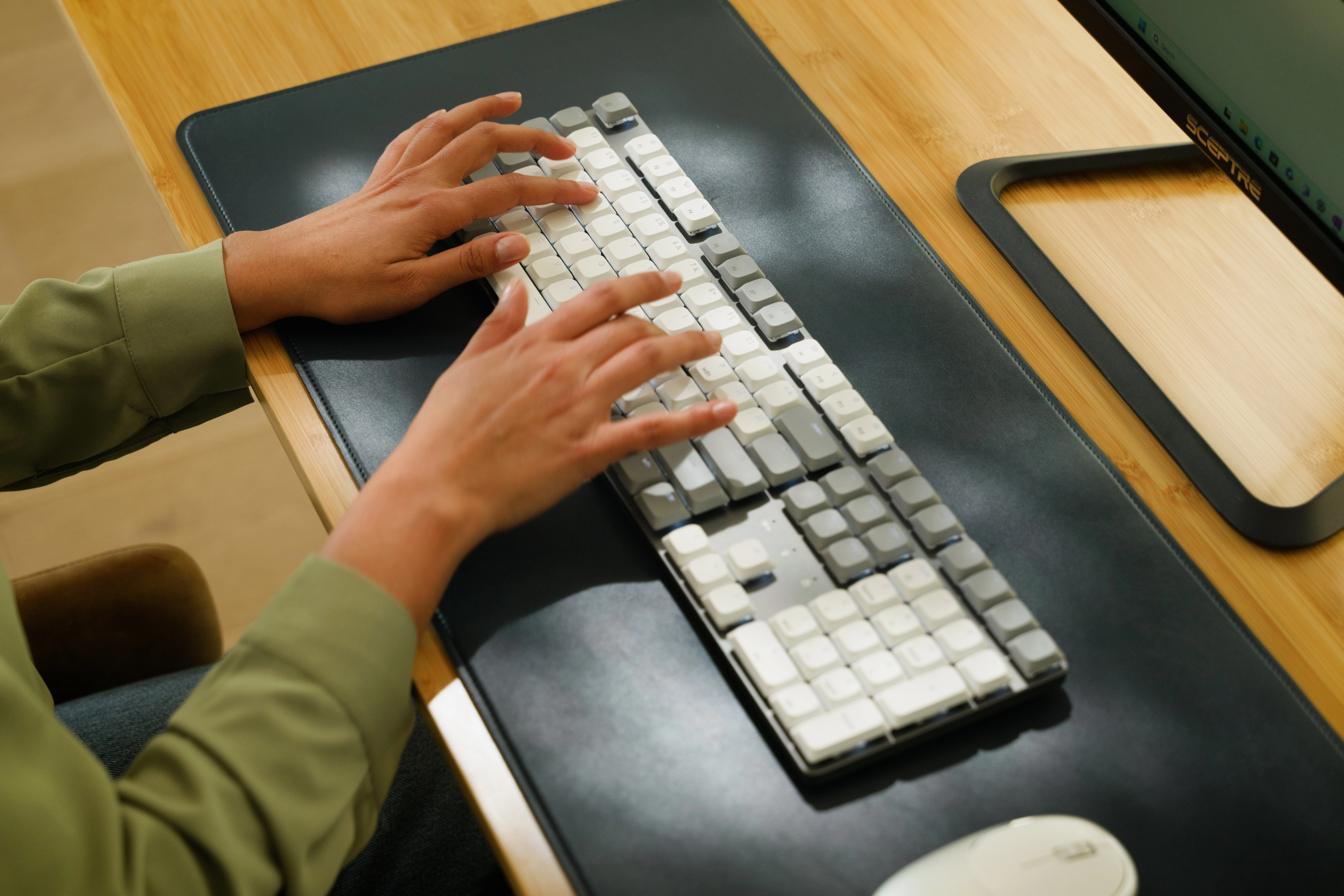 A person typing on a Satechi SM3 Slim Mechanical Backlit Bluetooth Keyboard.