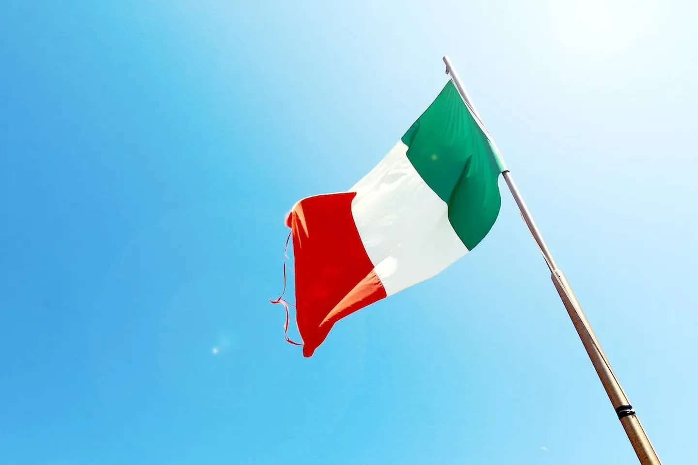 An Italian flag (green, white, and red) flying in the wind