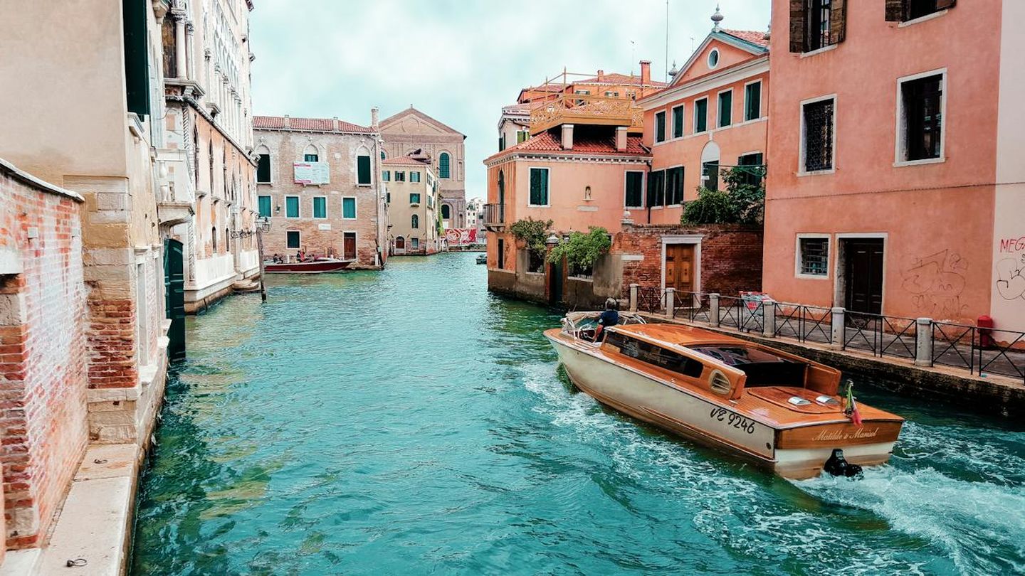 A shot of a Venetian canal with a taxi-boat gliding on the water amidst colorful buildings