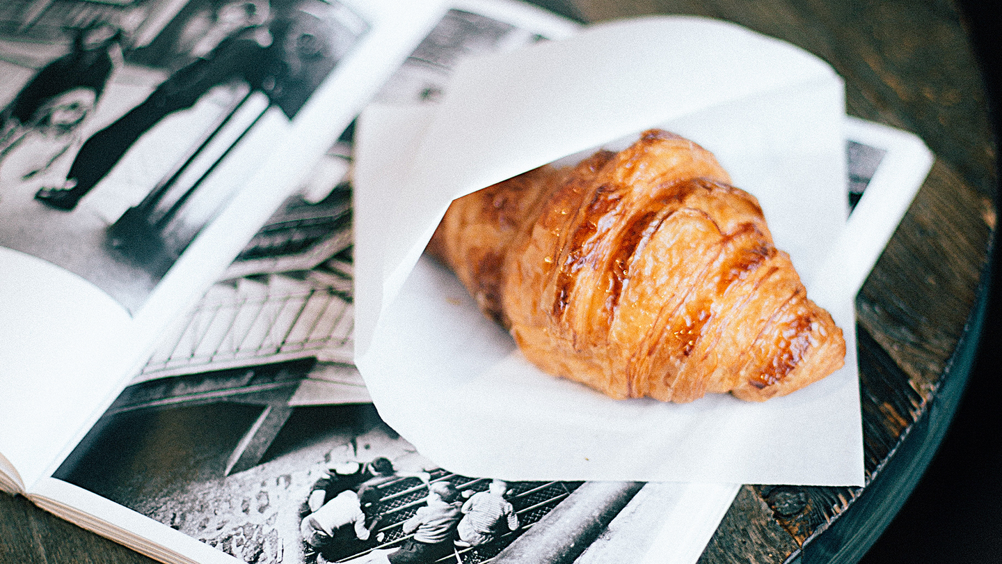 A croissant on a napkin on top of a table