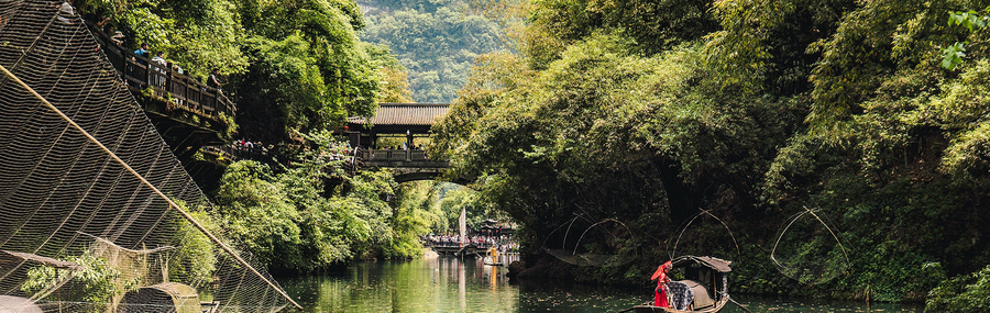 Historical  Chinese river boats sailing on the Yangtze River at the bottom of a bamboo-lined ravine