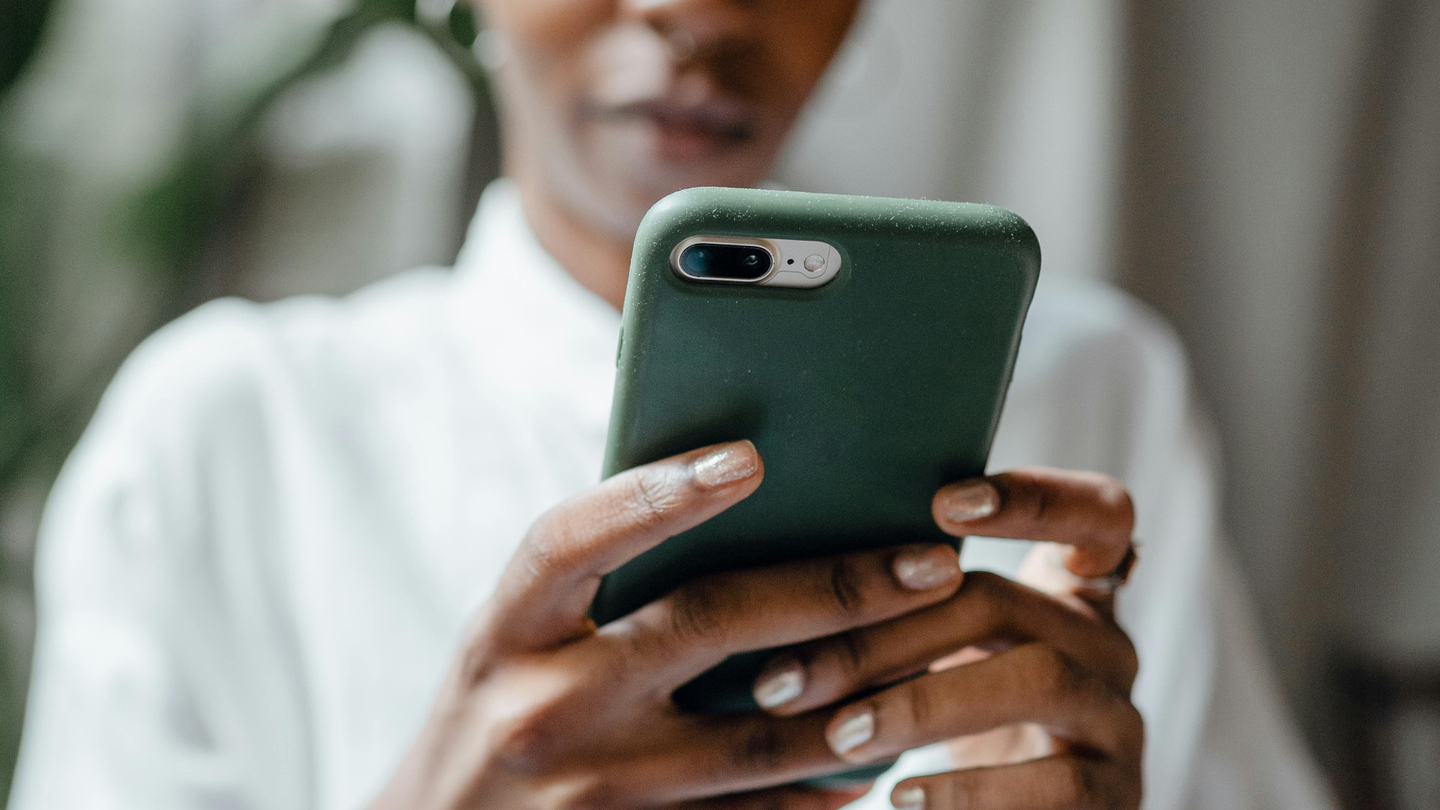 The back of a green phone as it is held in a woman's hands