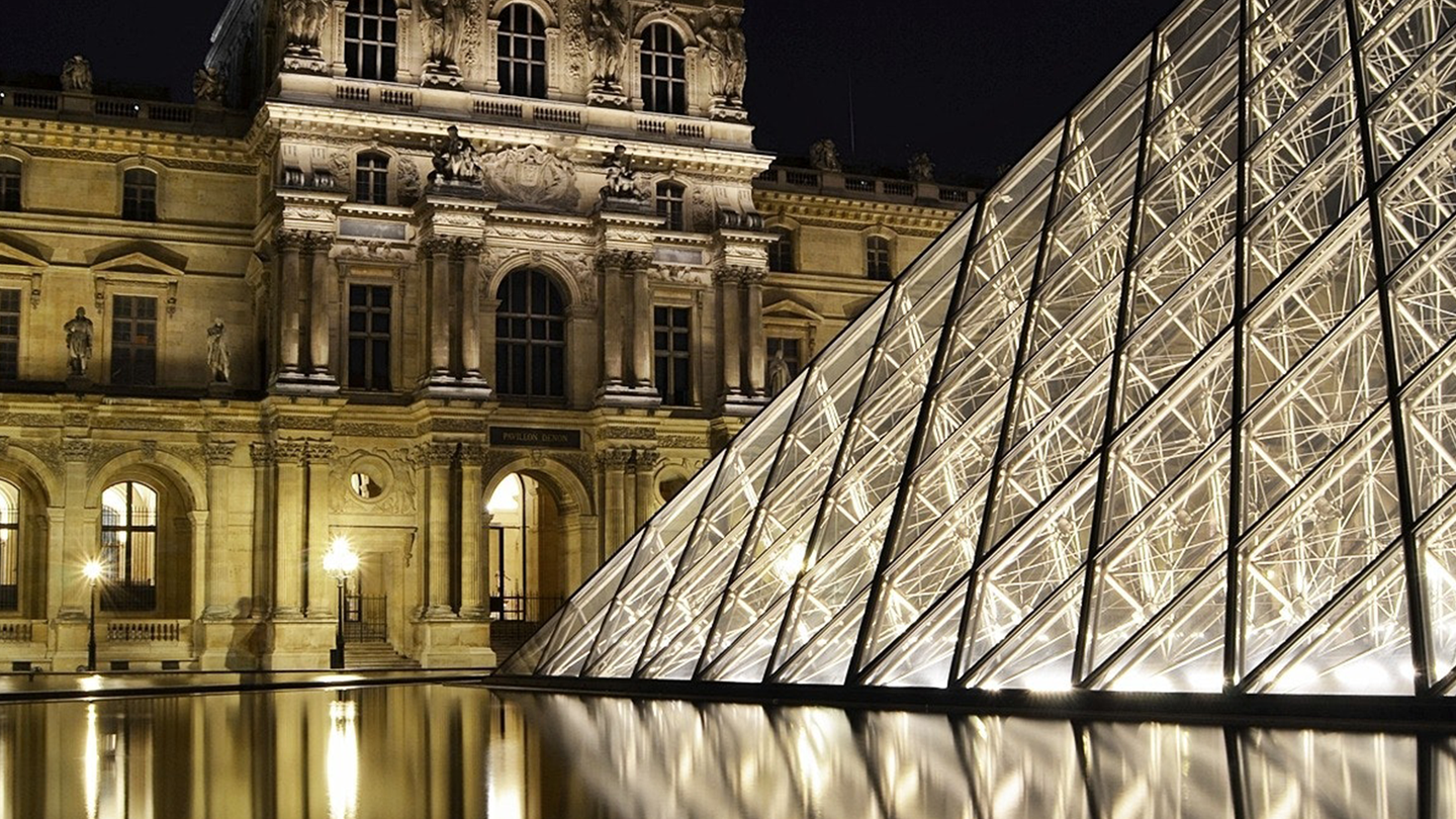 A picture of the glass pyramid in front of the Louvre museum photographed at night while all lit up