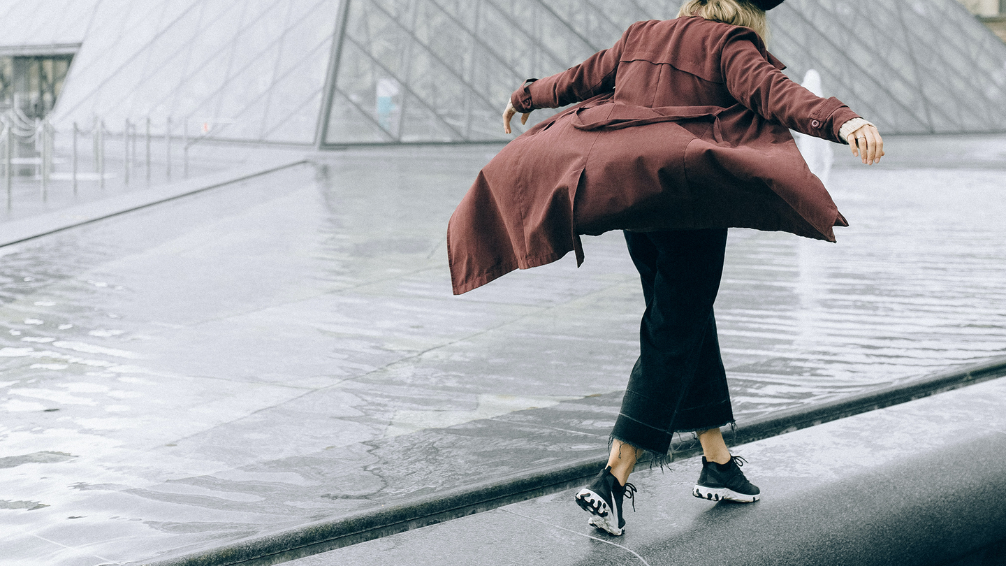 A tourist walking on the fountain in front of the Louvre