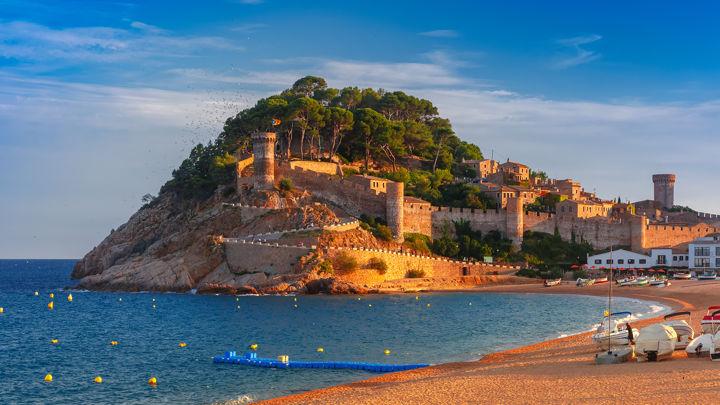 A historical medieval fortified building on top of a cliff overlooking the sea