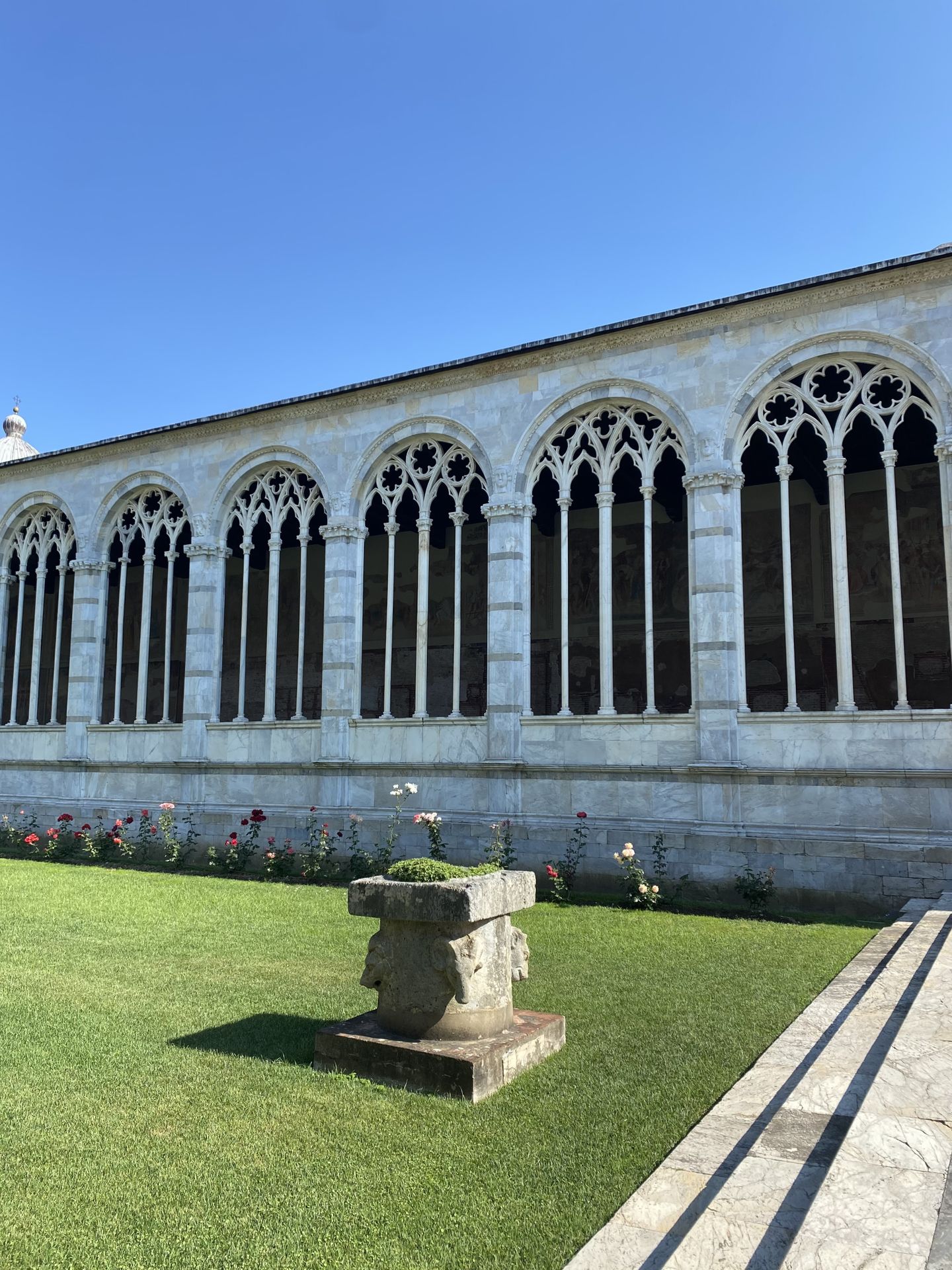 Detail of the cloister of the monumental cemetery in Pisa framed by tall windows in the Romanic architectural style