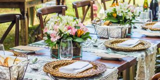 lush tropical bouquets adorn an outdoor table set with wicker plates for fine dining