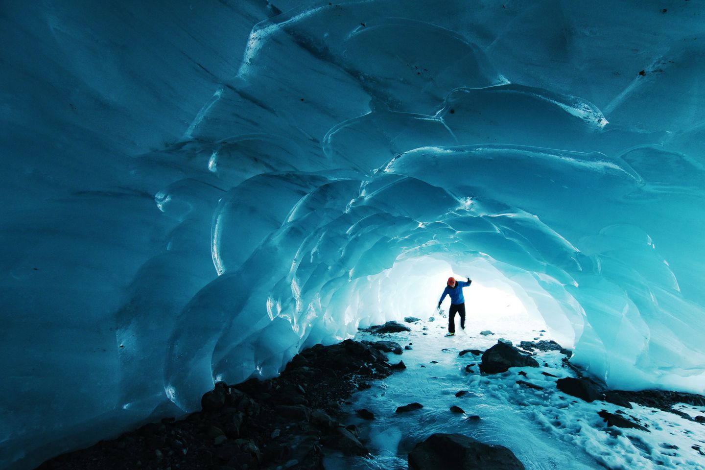 A man walking under a cave inside a glacier in Chugach National Forest, Seward, United States