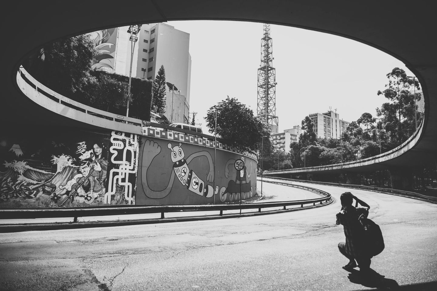 The exit of a curved urban street tunnel in brazil. The walls have creative murals on them.