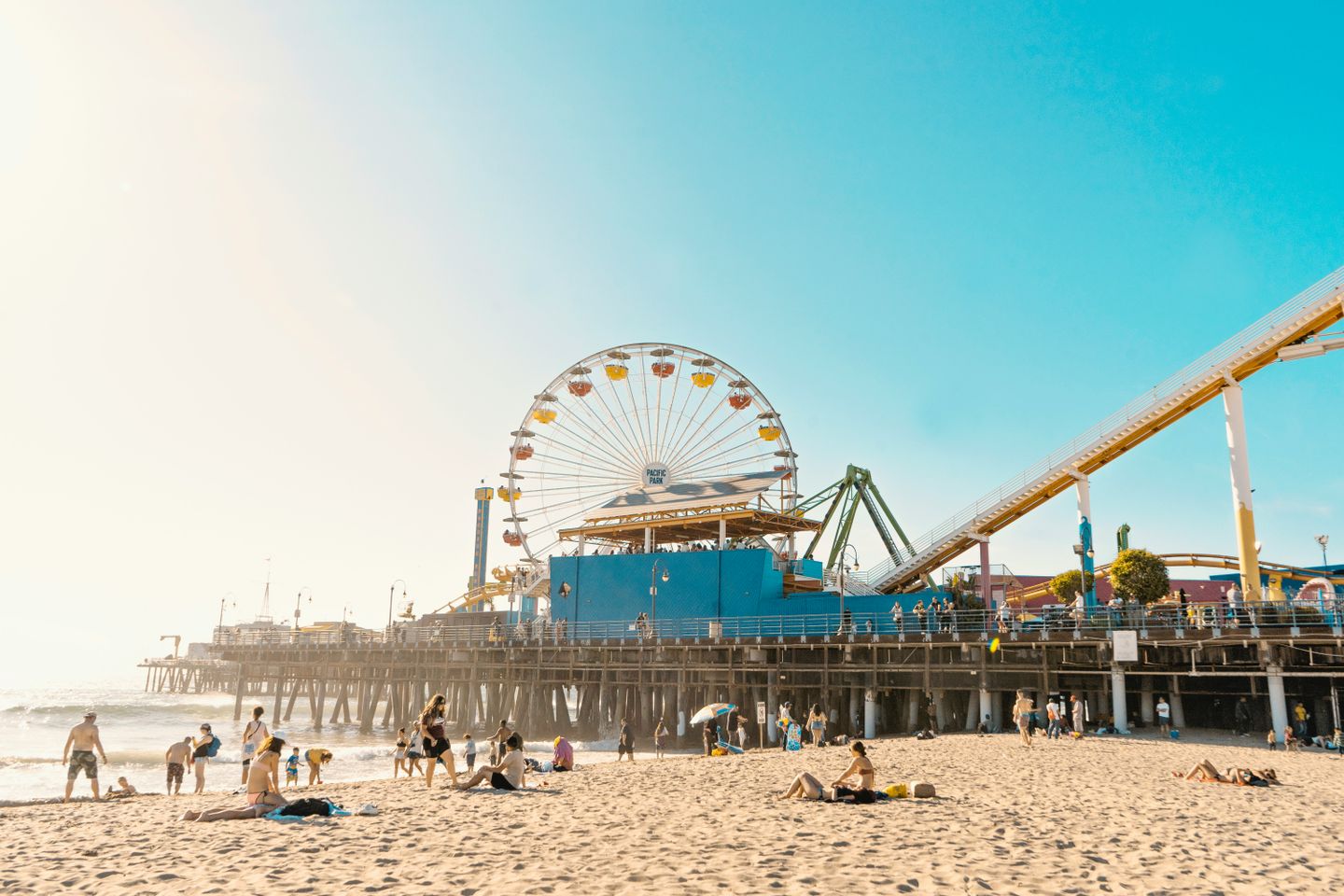 A ferris wheel in Santa Monica California with people lounging on the beach