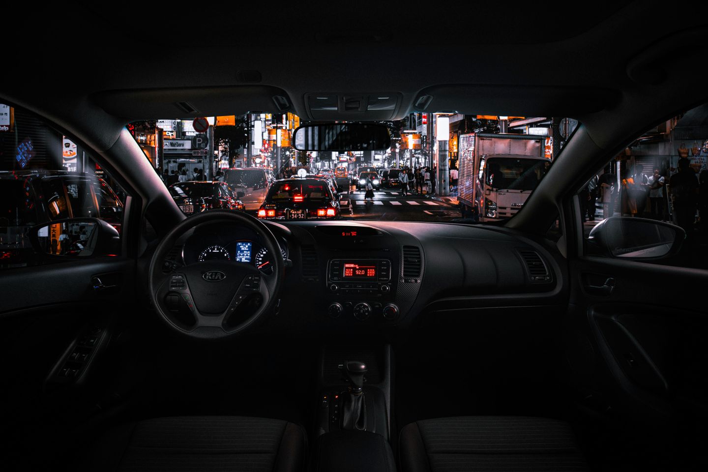 A nightscape view through the windshield of a car on a busy street in Tokyo