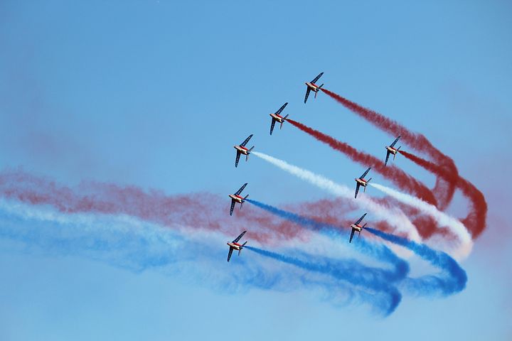 Eight airplanes in formation, releasing red, white, and blue trails.