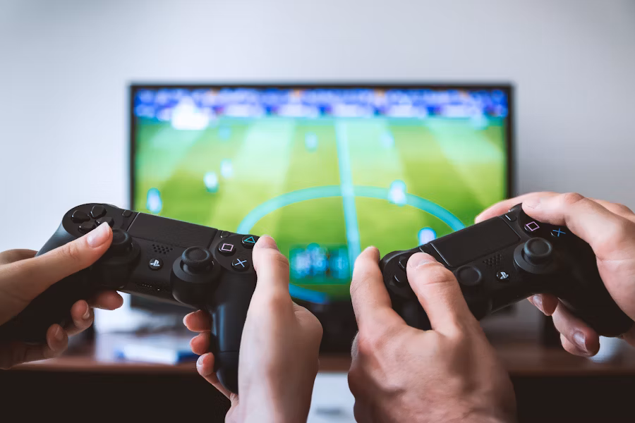 Two people playing a sports game on a Playstation.