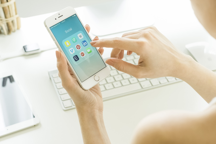 person holding a phone with several social media app on the screen
