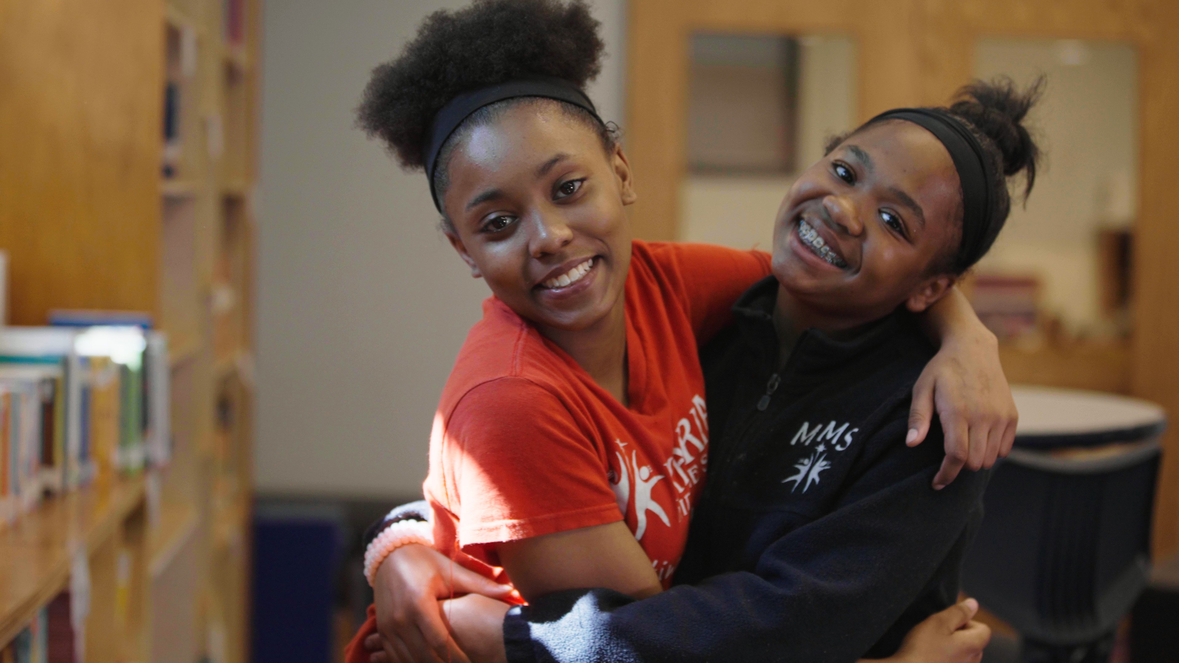 Two girls hugging and smiling.