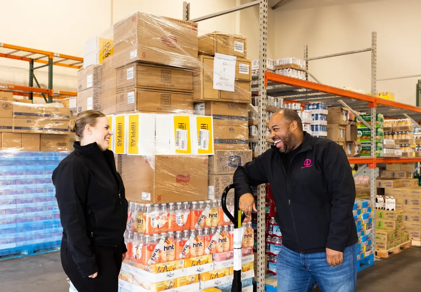 Two people laugh in conversation in a small business warehouse space