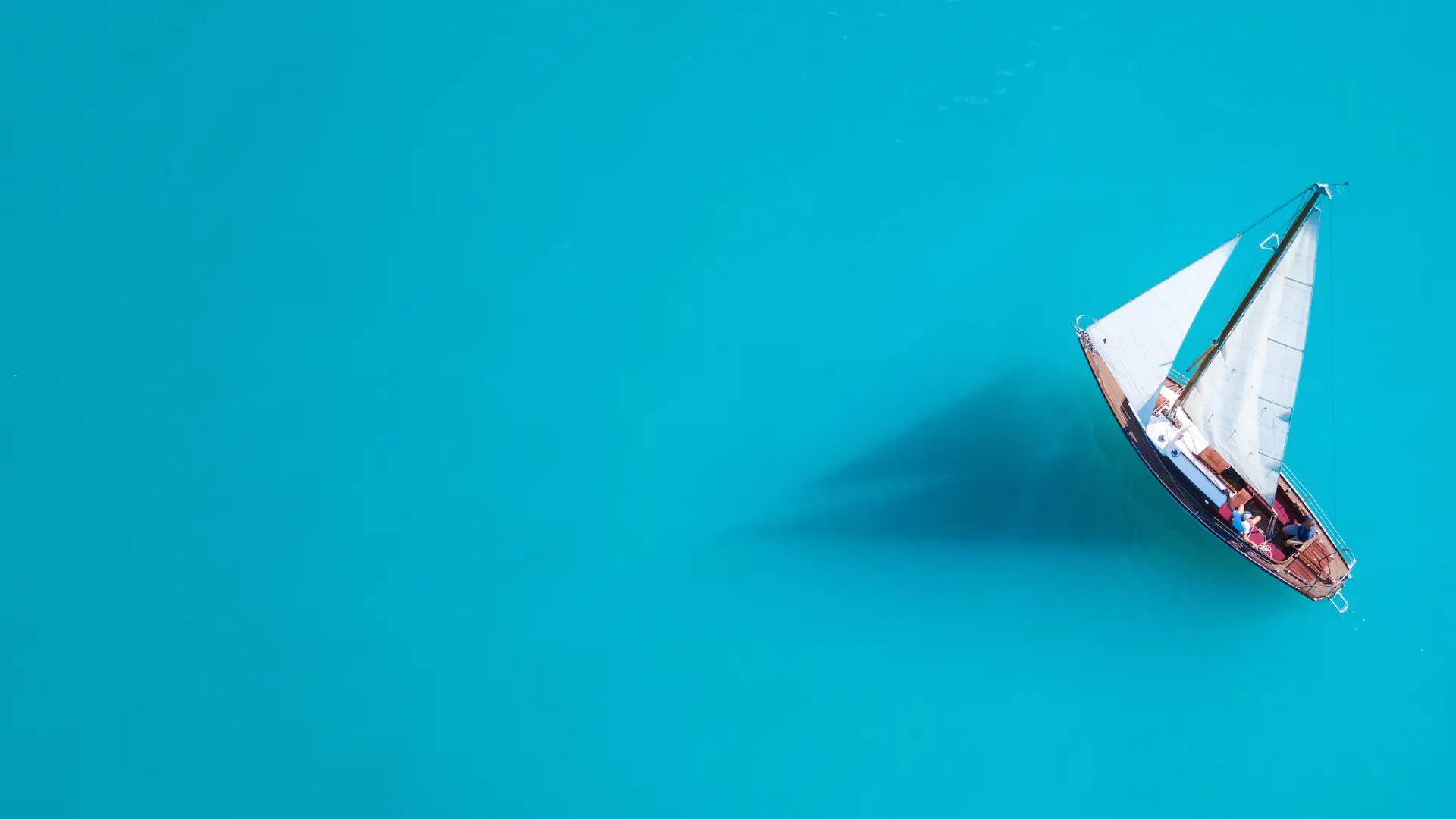 Aerial view of a sailboat on turquoise waters