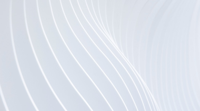 A close-up view of a white, curved architectural detail with repetitive wavy lines creating a sense of movement and texture.