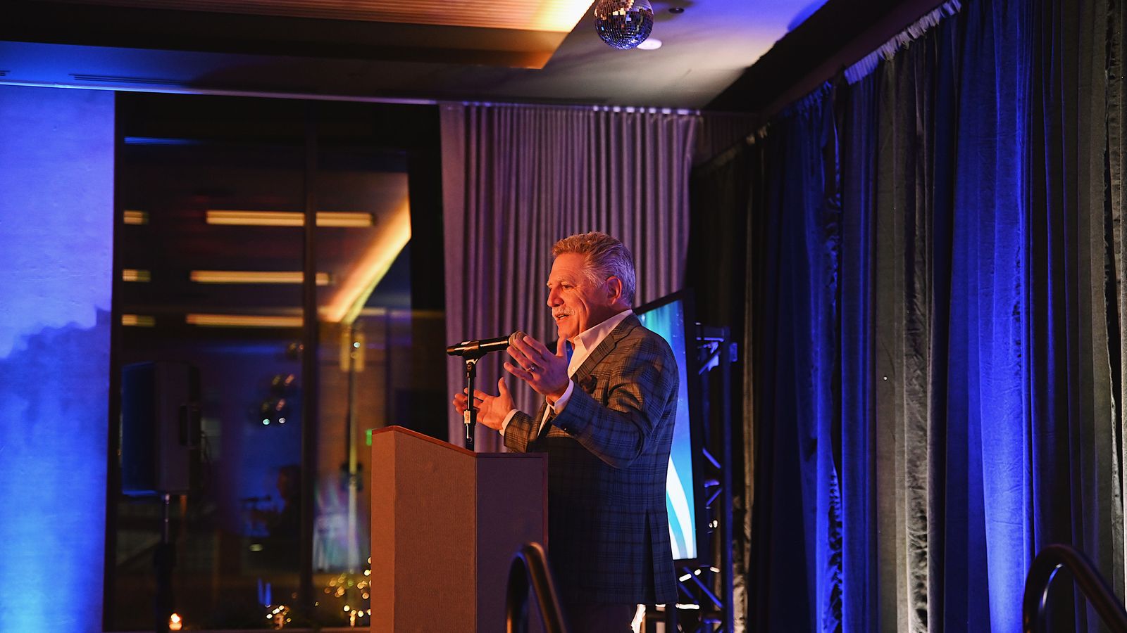 Walter Isenberg standing at a podium addressing an audience.