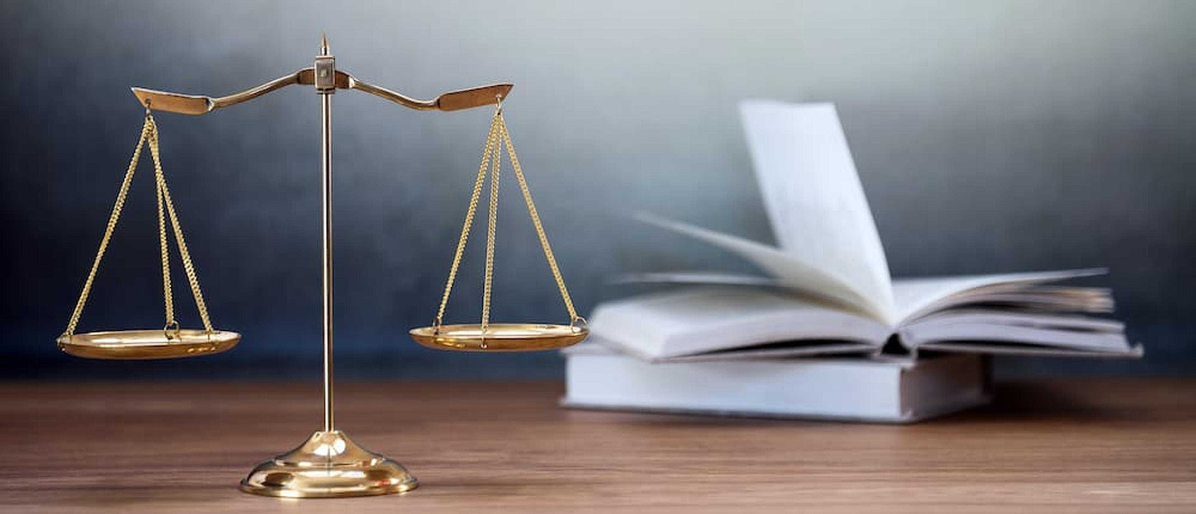 A gold scale of justice and an open law book on a wooden desk, illustrating legal regulations for dog bite euthanasia in New Mexico.