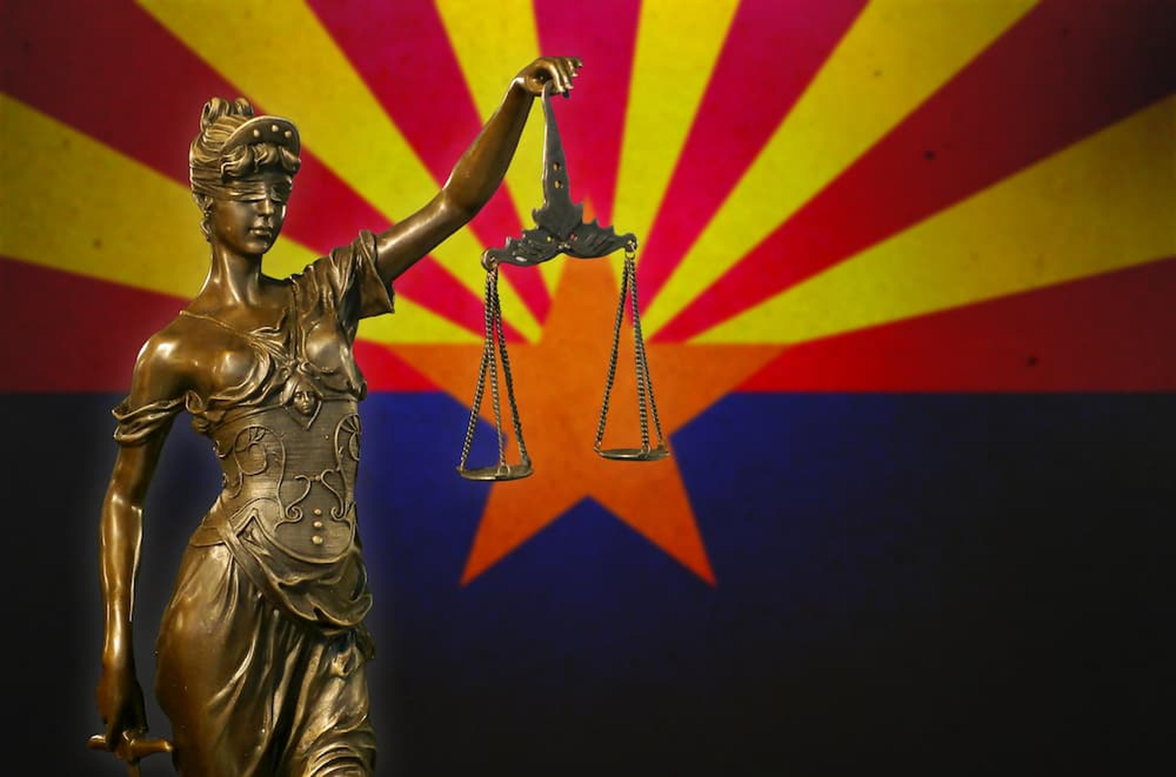 A bronze Lady Justice statue set against the Arizona state flag, illustrating legal rights and Arizona pedestrian laws for accident victims.