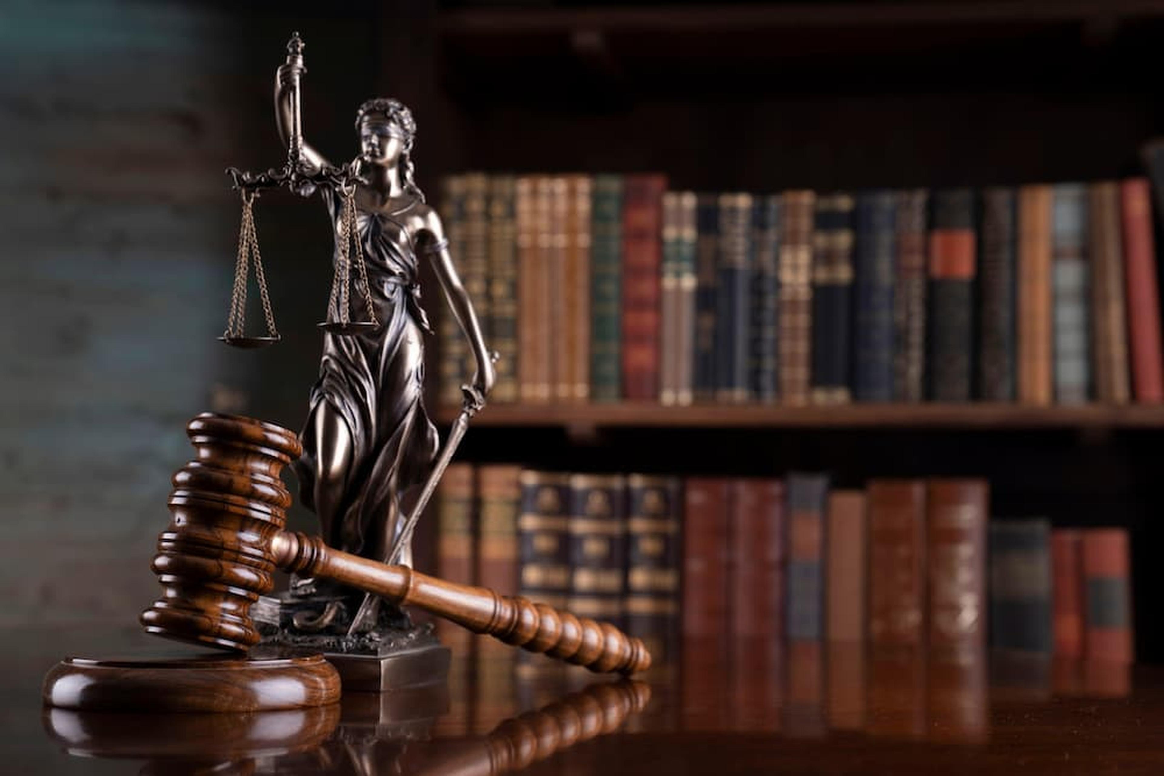 A bronze Lady Justice statue and a wooden gavel in front of a law library, representing legal consultation for Arizona dog bite law and euthanasia regulations.
