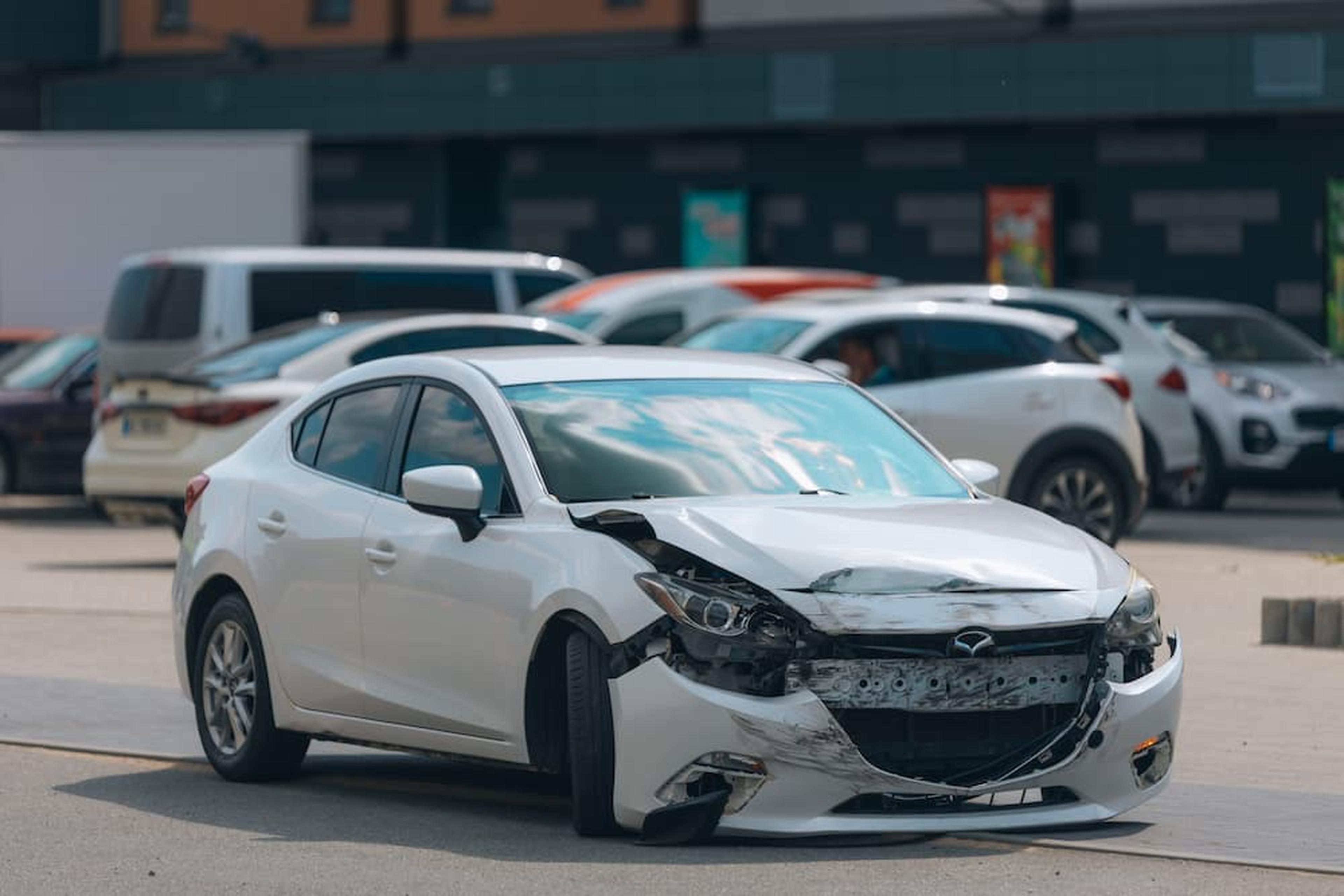 A white sedan with severe front-end damage after a collision, illustrating what to do after a car accident in Arizona for insurance claims.
