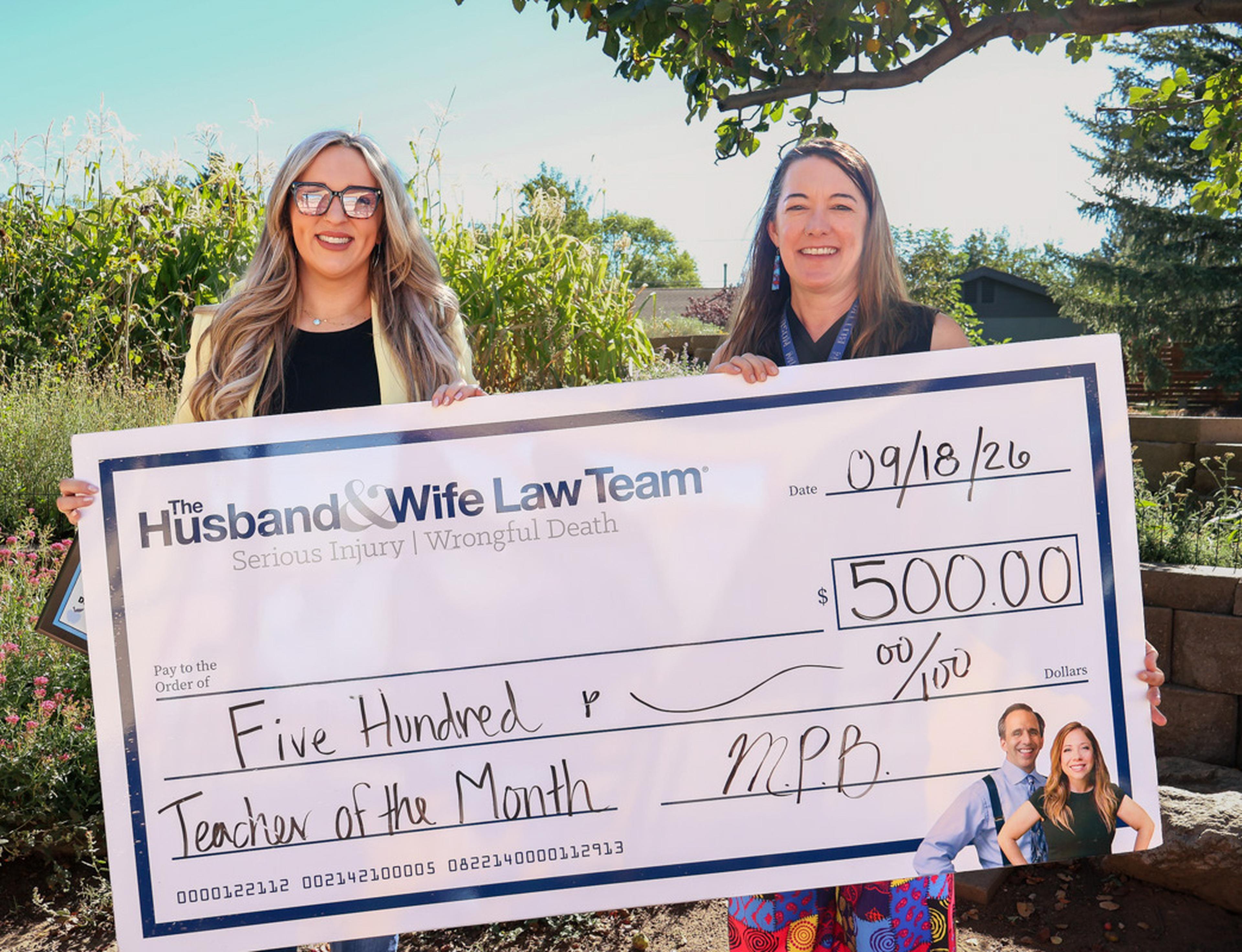 Jen from the Husband & Wife Law Team presents Ms. Bottke with a $500 Teacher of the Month award, recognizing her dedication to inspiring and supporting students at Puente de Hózhó Elementary.