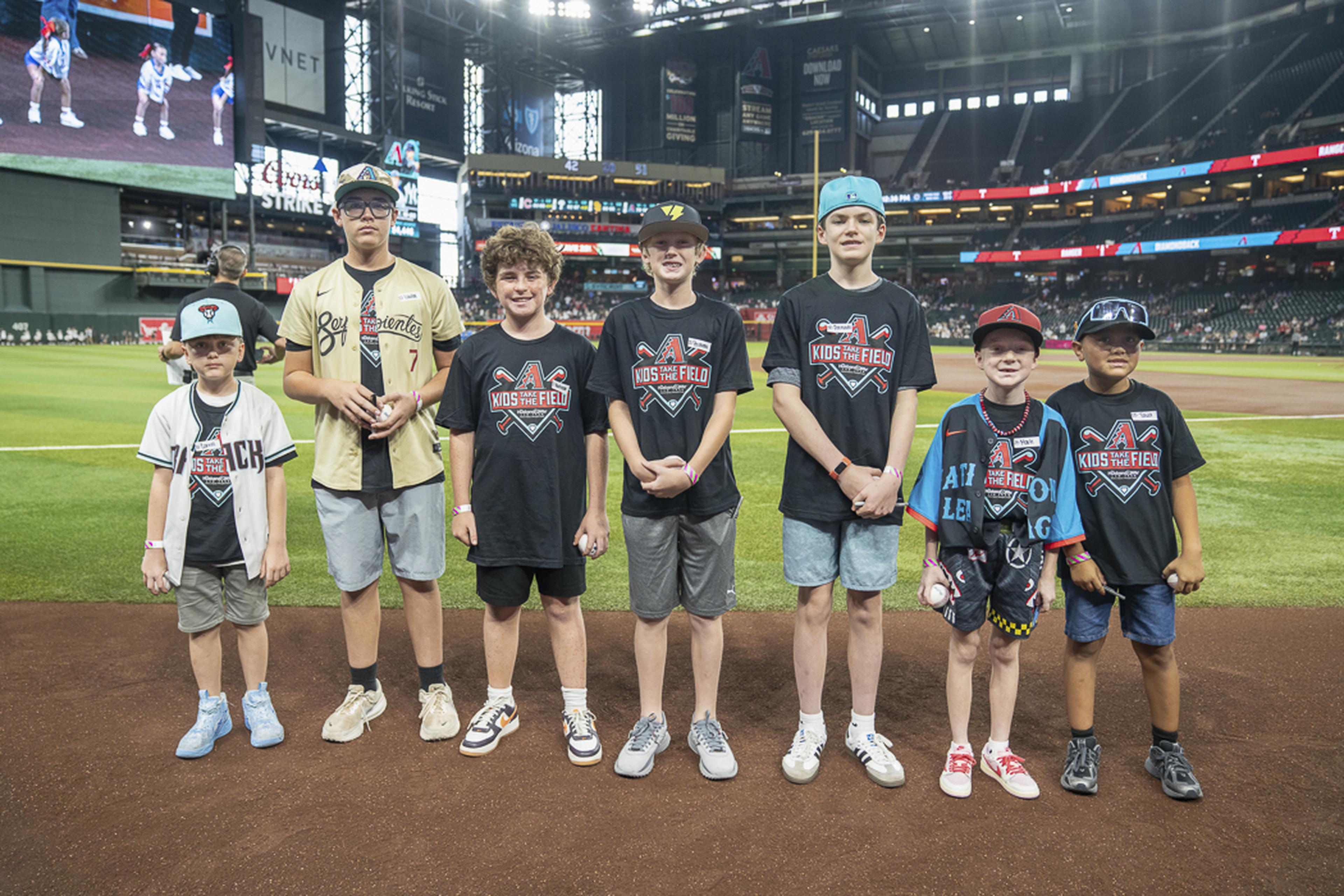 Seven Kids Take the Field participants gather near home plate, sharing smiles and excitement as they enjoy a once-in-a-lifetime experience at Chase Field.