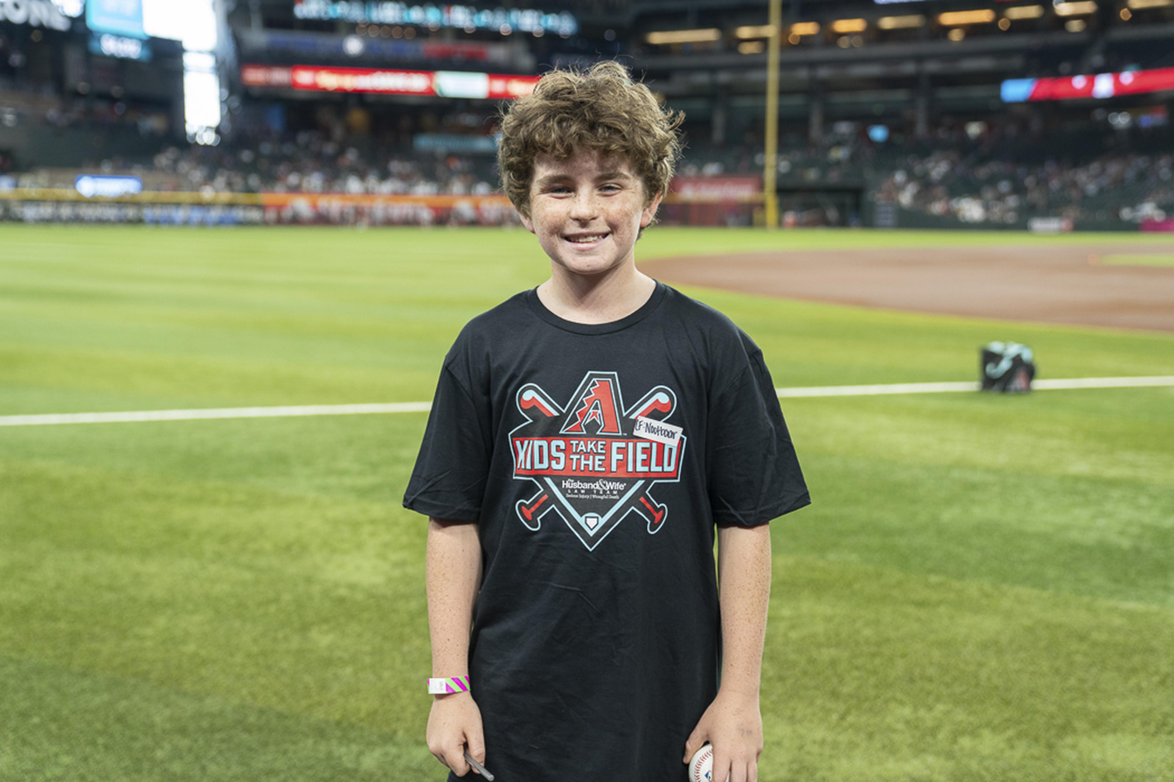 With a baseball in hand and excitement on his face, a young fan celebrates his Kids Take the Field experience while creating unforgettable memories at Chase Field.