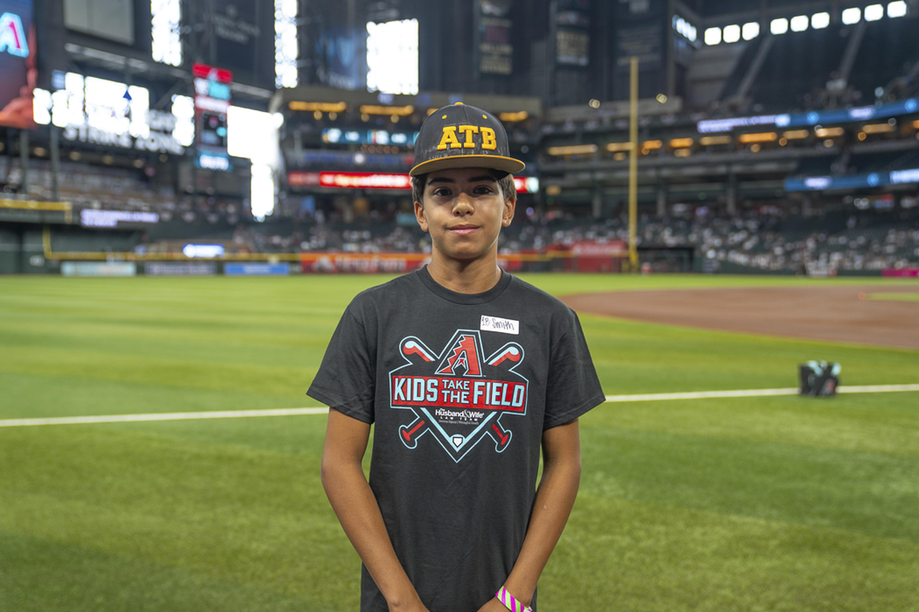 A young Kids Take the Field participant stands proudly on the field, soaking in the excitement of a once-in-a-lifetime experience at Chase Field before the game.