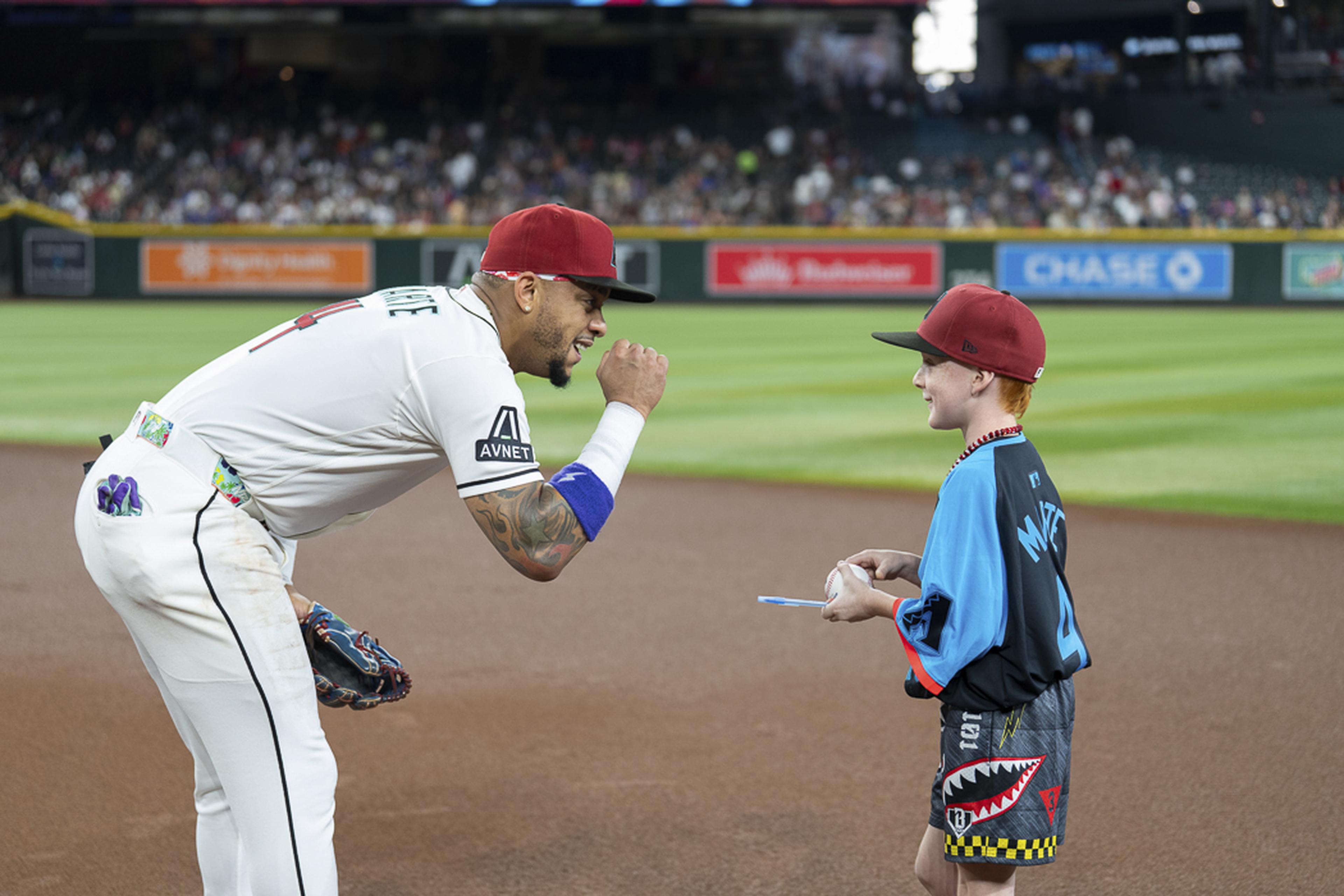 A special on-field moment unfolds as a young fan exchanges a fist bump with an Arizona Diamondbacks player, making his Kids Take the Field experience even more unforgettable