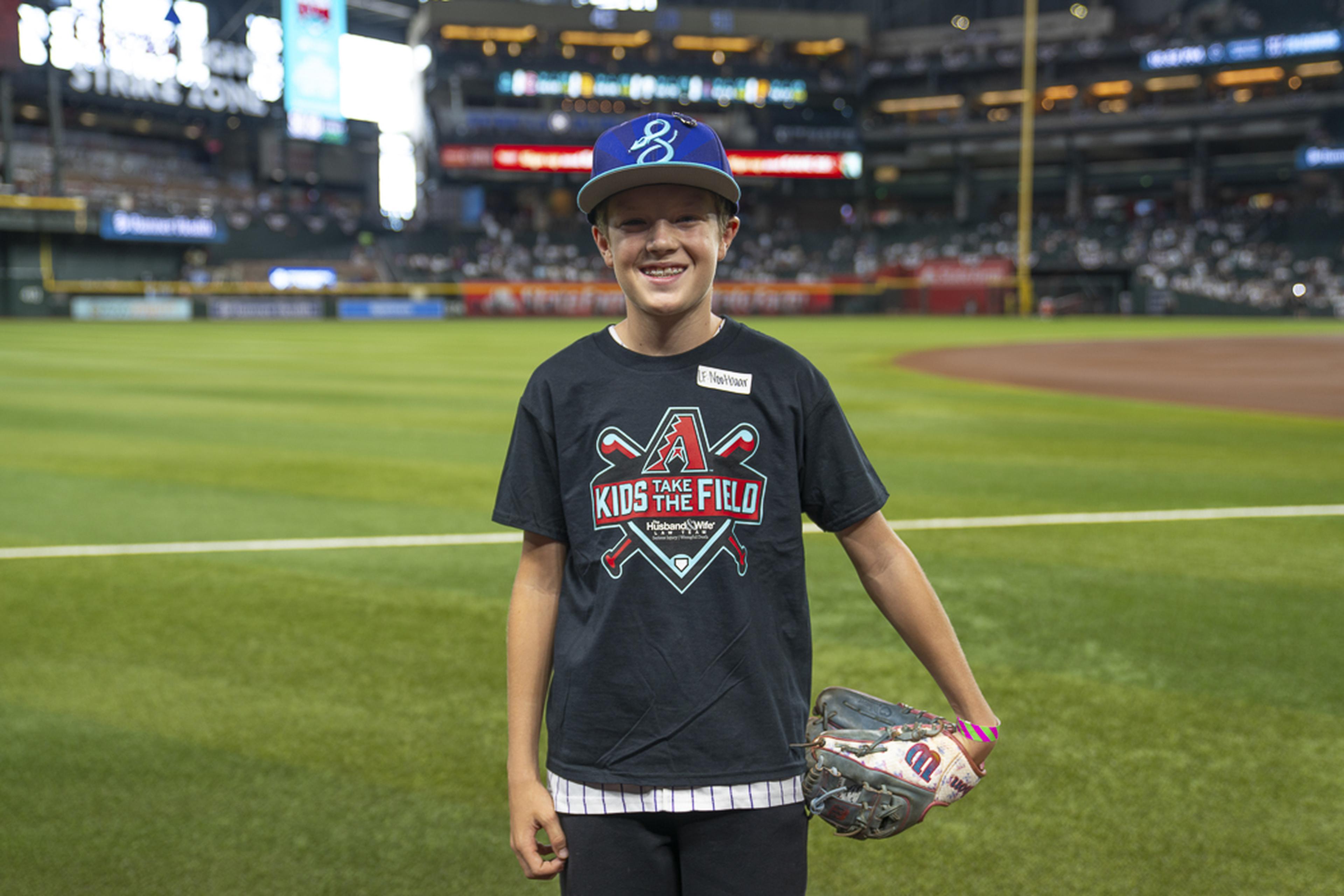 A young Kids Take the Field participant smiles proudly with his glove in hand, enjoying a memorable day on the field at Chase Field before the game.