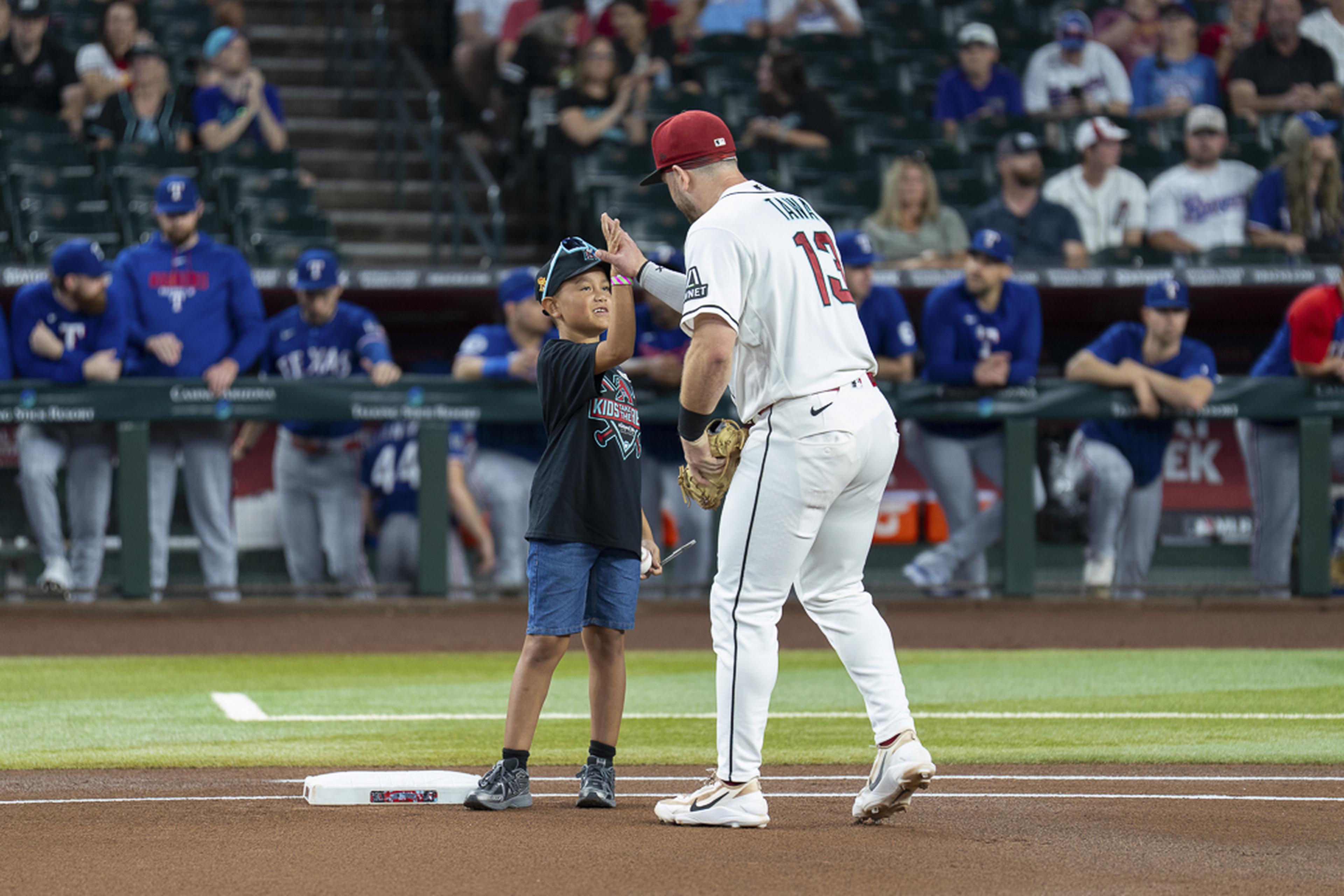 A young fan lights up with excitement as Arizona Diamondbacks infielder Tim Tawa greets him on the field, making his Kids Take the Field experience even more unforgettable.