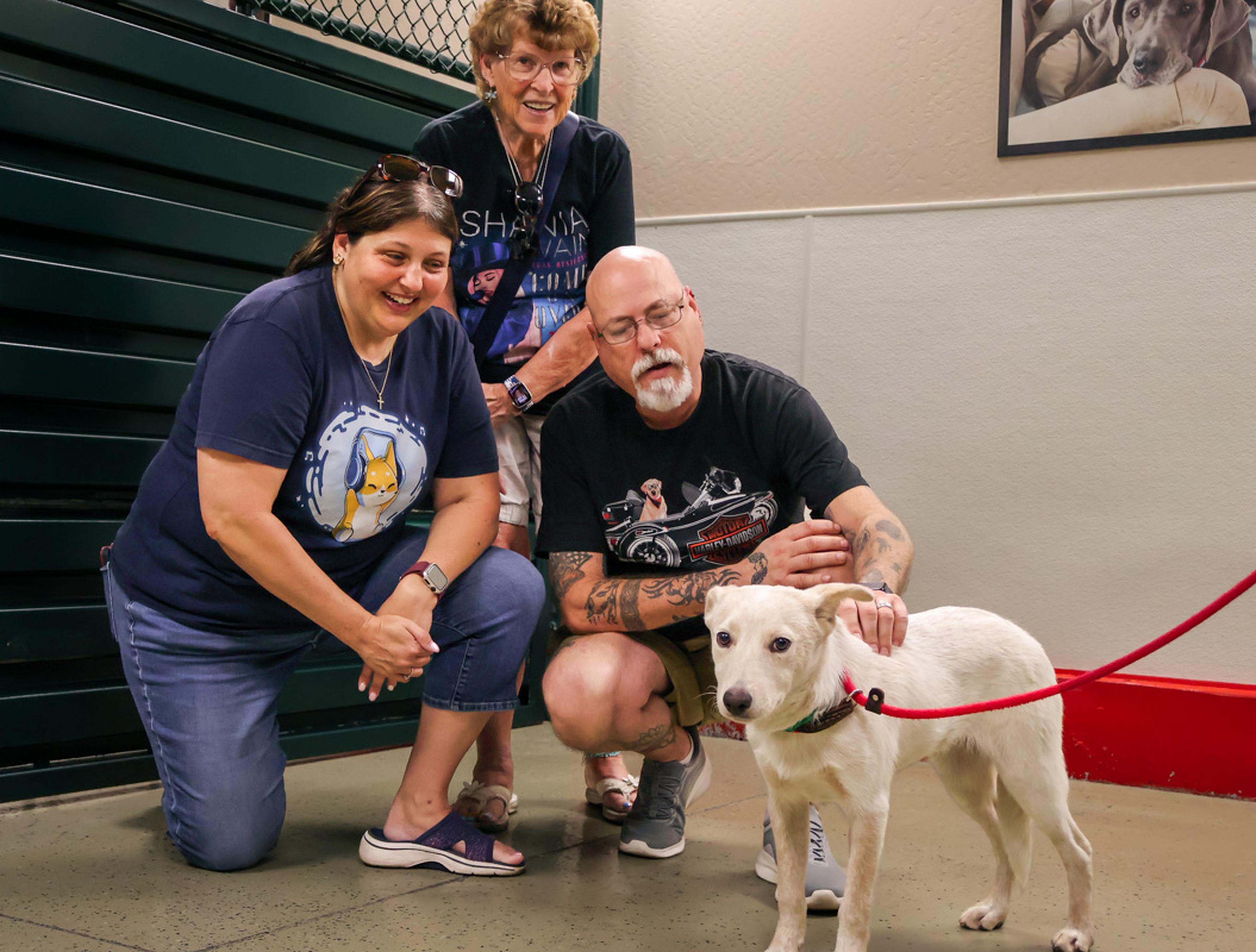 Three community members gather around an adorable dog at the Husband & Wife Law Team’s HALO Adoption Event, sharing smiles and affection while helping pets find loving homes.