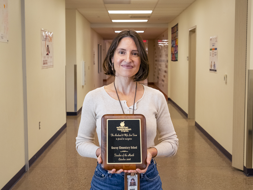 Mrs. Vargas-Portley proudly displays her Teacher of the Month plaque from the Husband & Wife Law Team, celebrating her dedication to students at Kearny Elementary School.