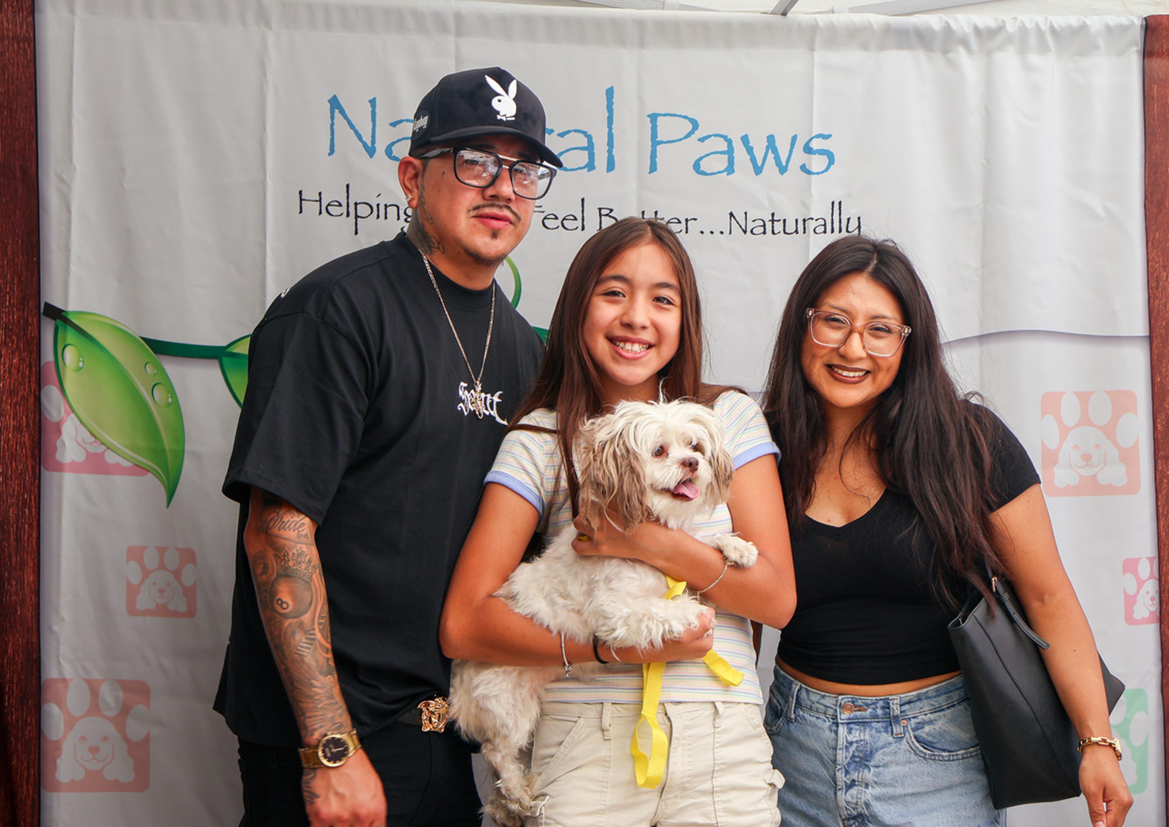 Smiles all around as a family welcomes a new furry companion at the Husband & Wife Law Team’s HALO Adoption Event, creating a heartwarming moment in front of the Natural Paws backdrop.