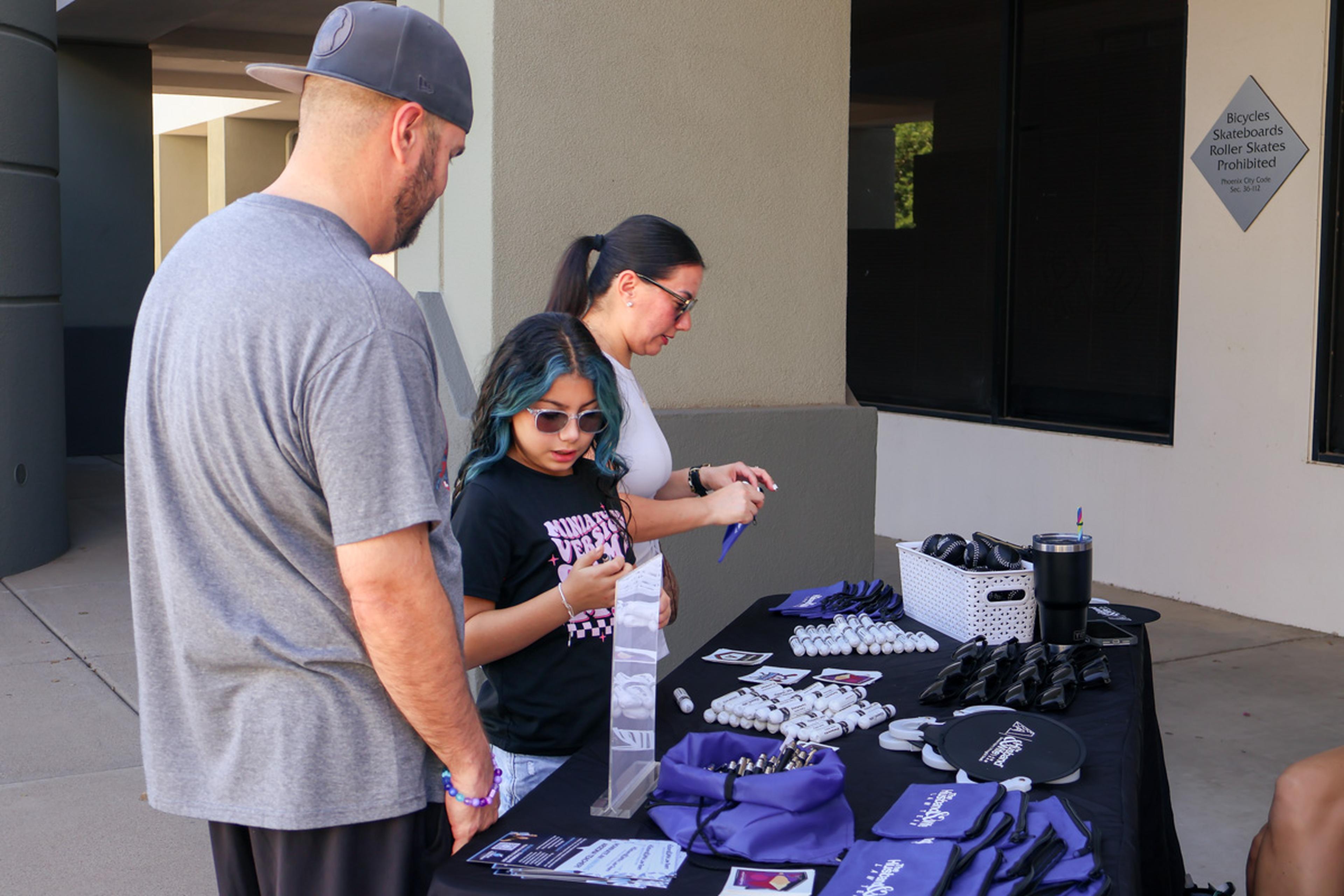 A family browses Husband & Wife Law Team giveaways and event materials at the HALO Adoption Event, enjoying a day dedicated to community involvement, pet adoption, and family-friendly fun.