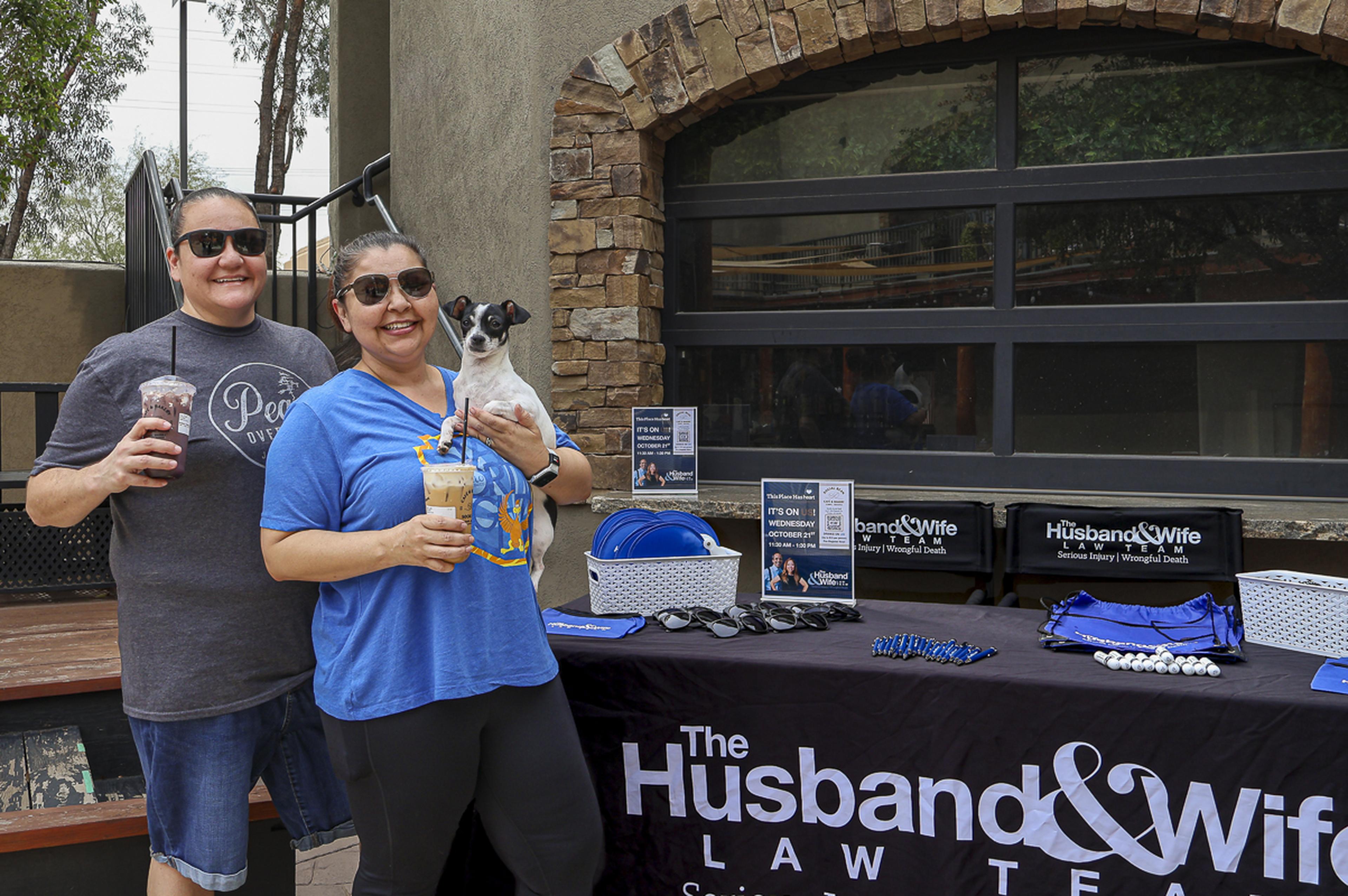 Two guests enjoy coffee and sunshine with their pup during the Husband & Wife Law Team’s HEART event at Social Bean Café & Bakery.
