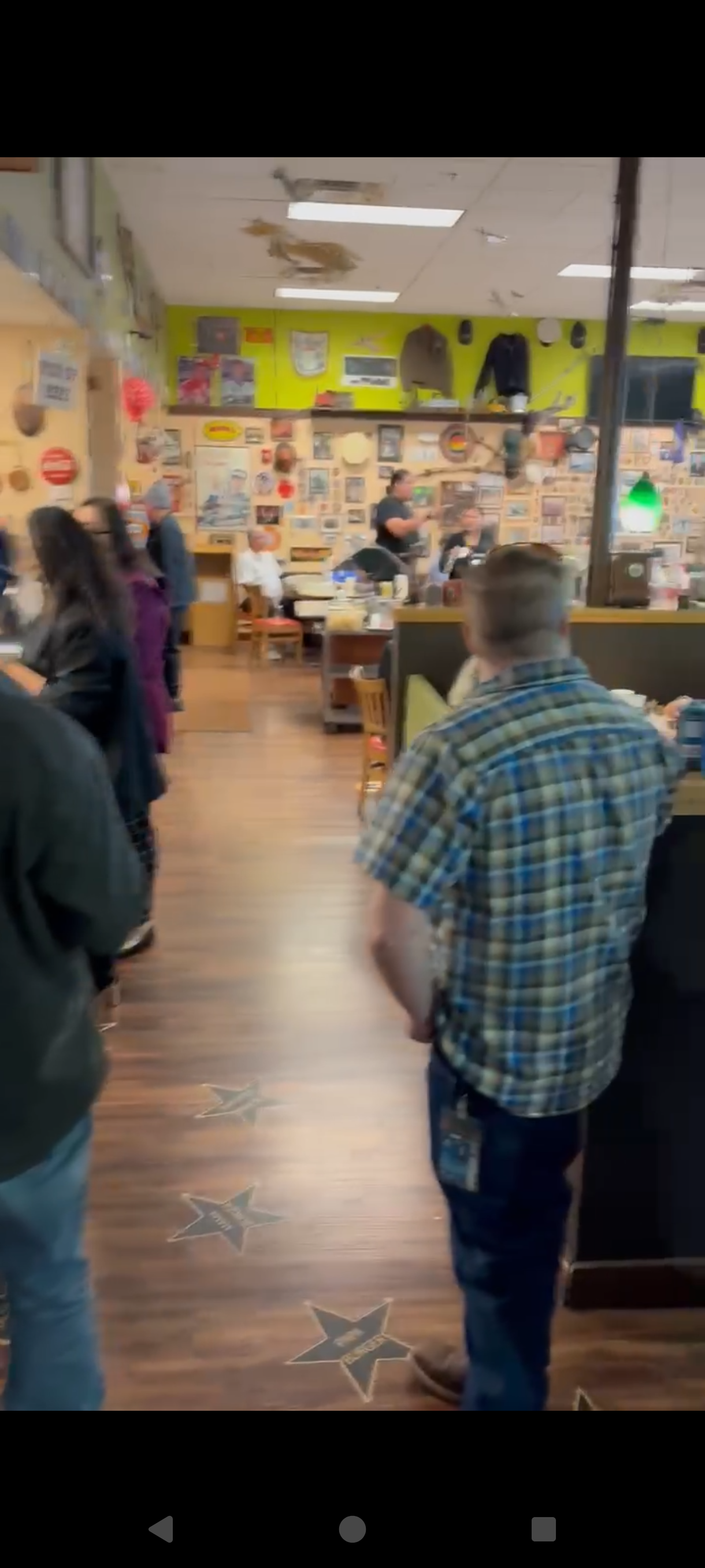 People inside The Grill with wooden flooring and walls decorated with memorabilia.
