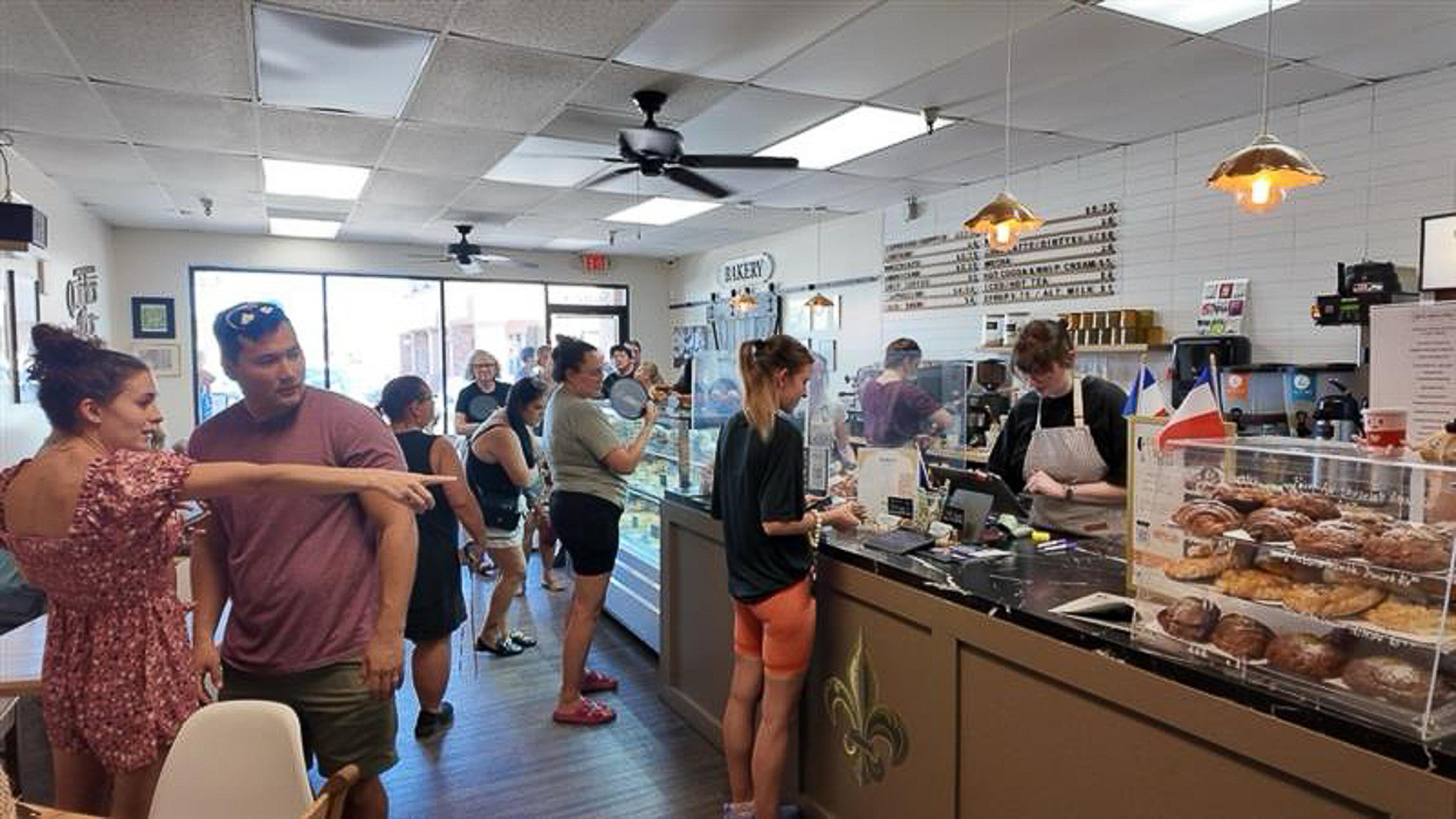 Guests line up inside Quiches & Pies Bakery as fresh pastries fill the display case, creating a welcoming atmosphere during the Husband & Wife Law Team’s HEART event.