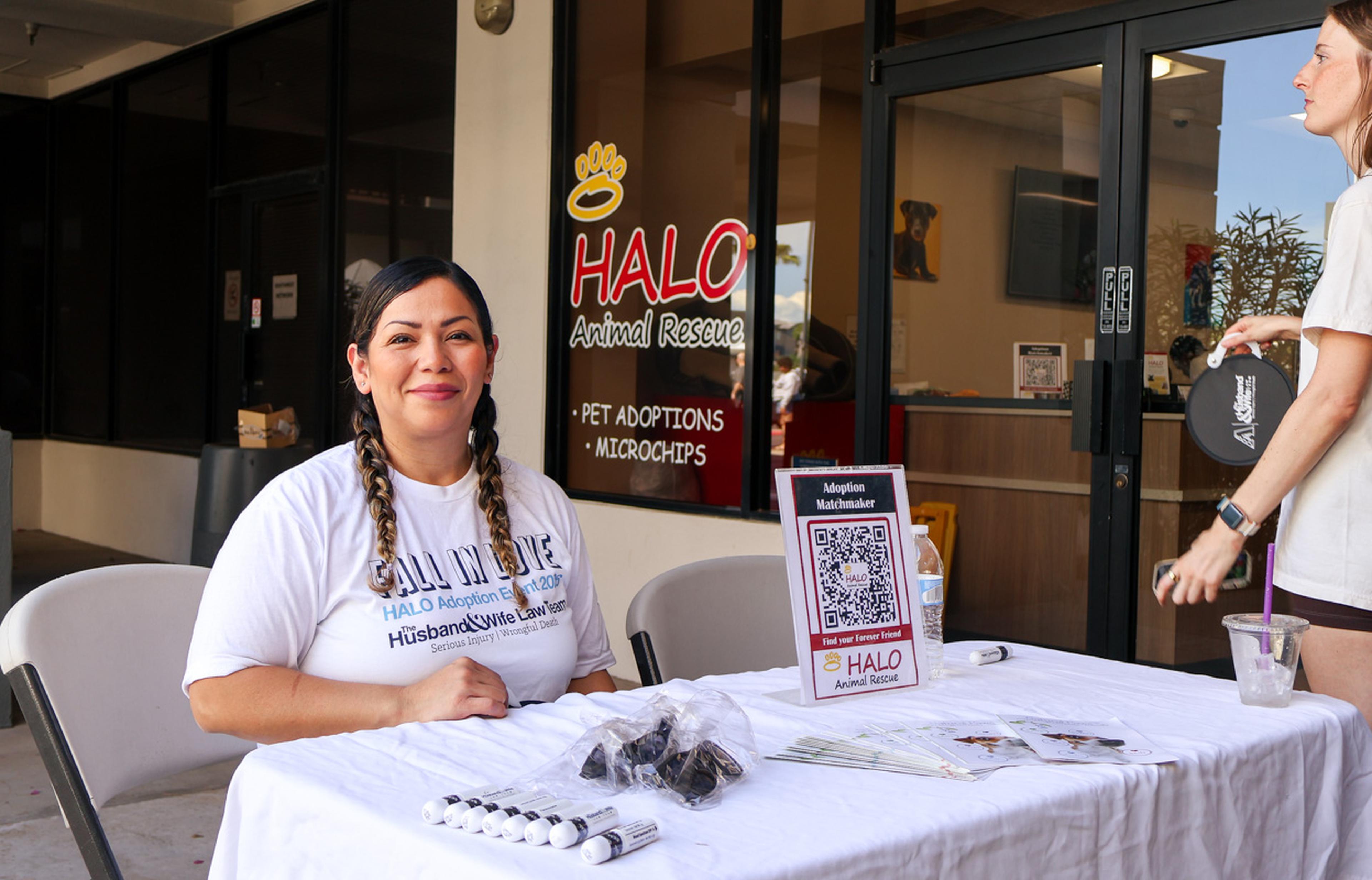 A Husband & Wife Law Team volunteer welcomes visitors at the HALO Adoption Event, sharing information on pet adoptions, microchipping services, and resources that help pets find loving forever homes.