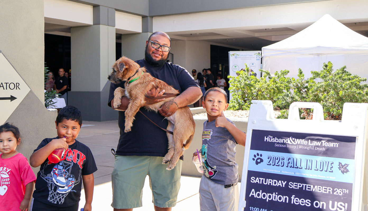 A proud family celebrates the adoption of a new four-legged companion at the Husband & Wife Law Team’s HALO Adoption Event, marking the beginning of a new chapter filled with love, laughter, and a forever home.