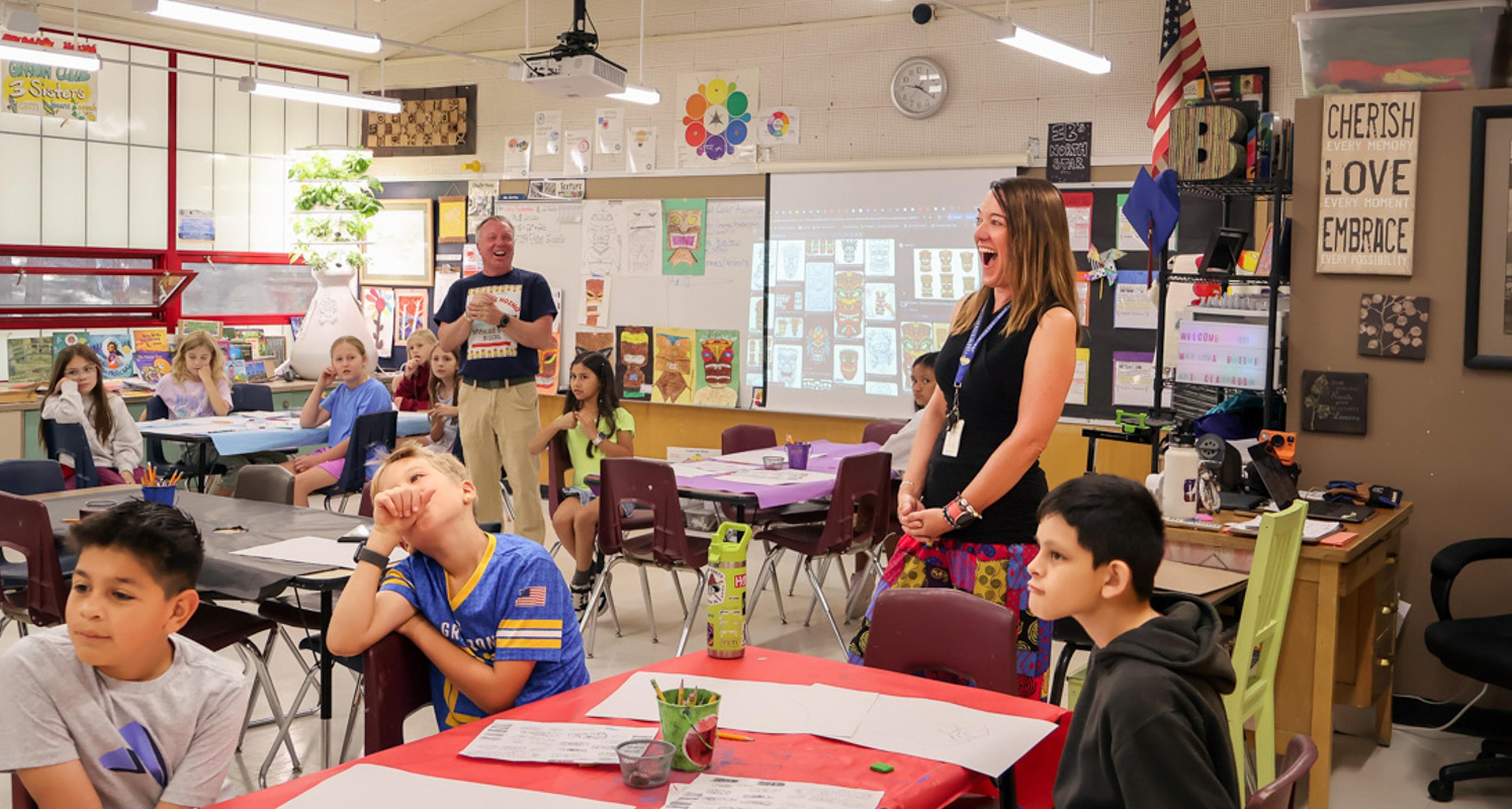A surprised and smiling Ms. Bottke is recognized with a Teacher Appreciation Award from the Husband & Wife Law Team, celebrating her dedication to inspiring and educating students at Puente de Hózhó Elementary.