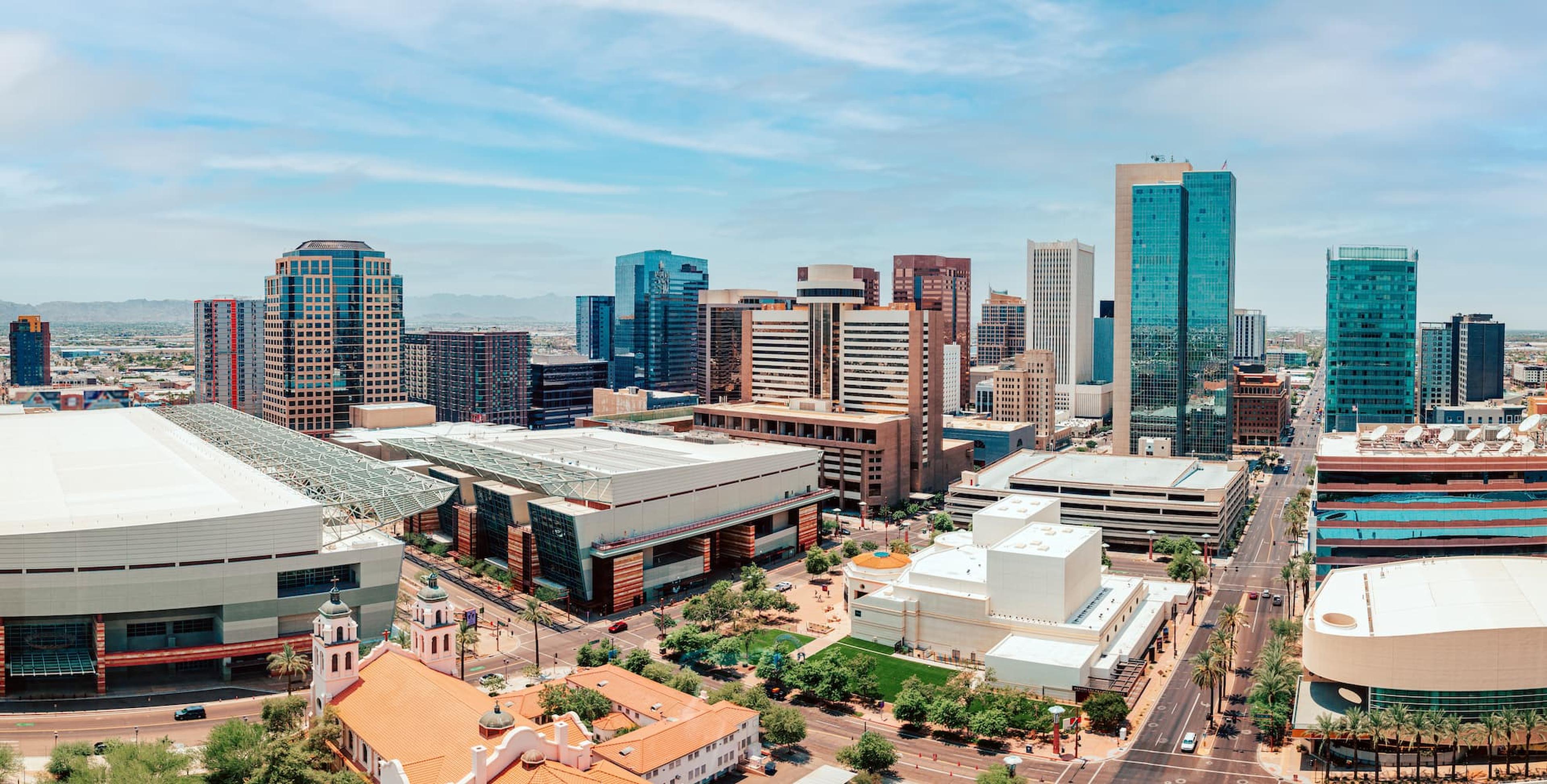 Aerial view of downtown Phoenix, Arizona, with high-rise towers, the convention center and wide city streets under a blue sky
