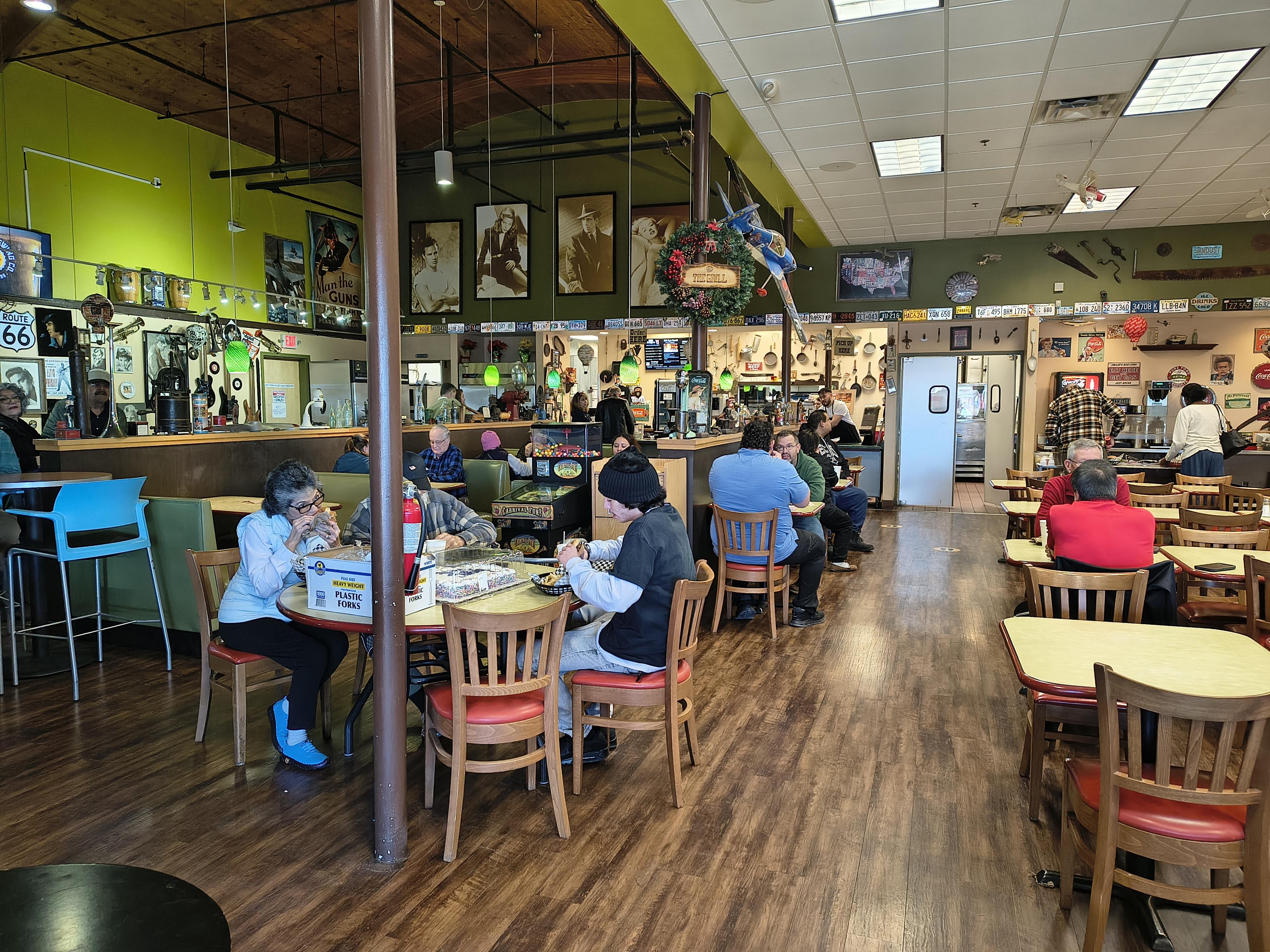 People dining at The Grill, eclectic decor, and wooden flooring, creating a cozy atmosphere.