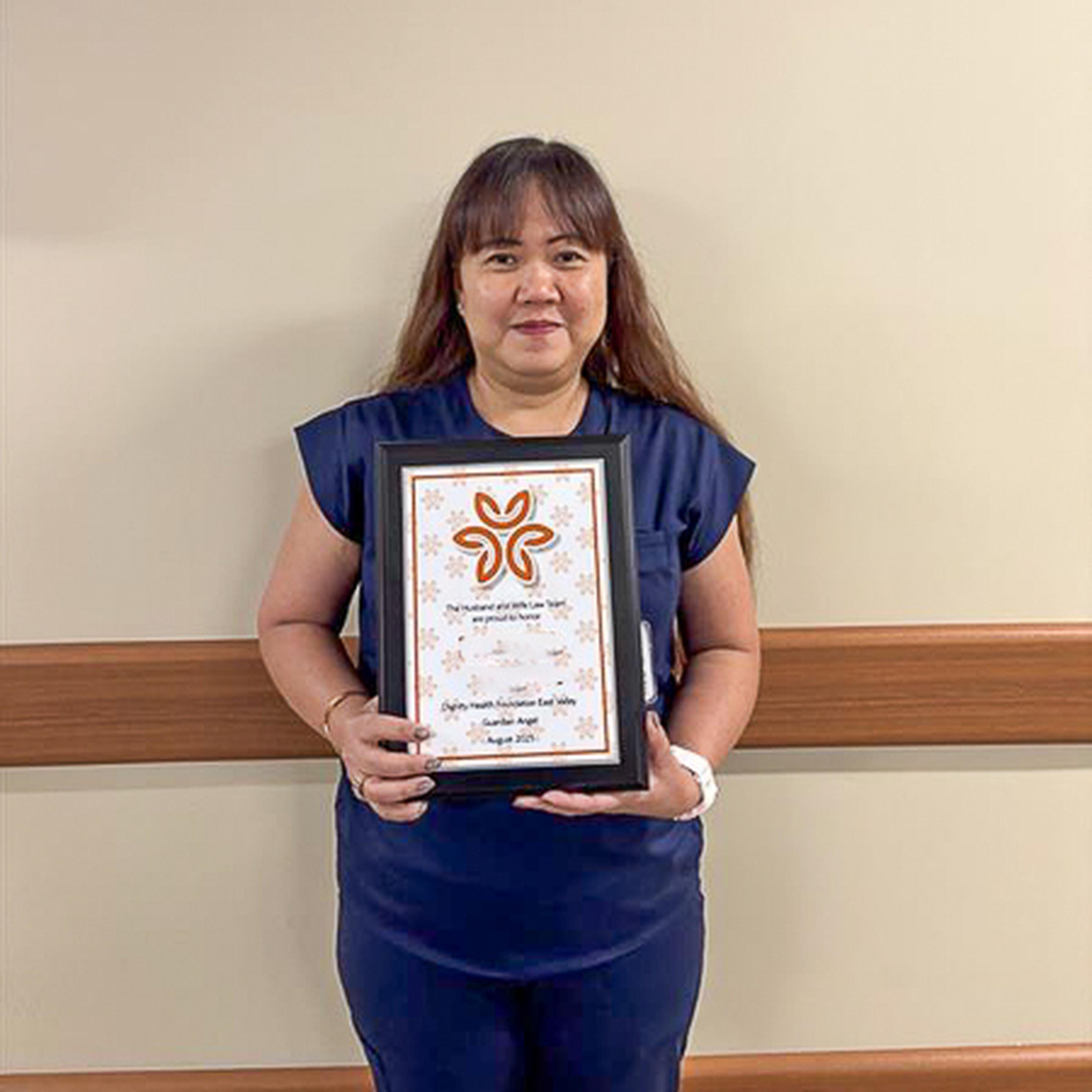 Nurse Mitchel holding her Guardian Angel winner plaque