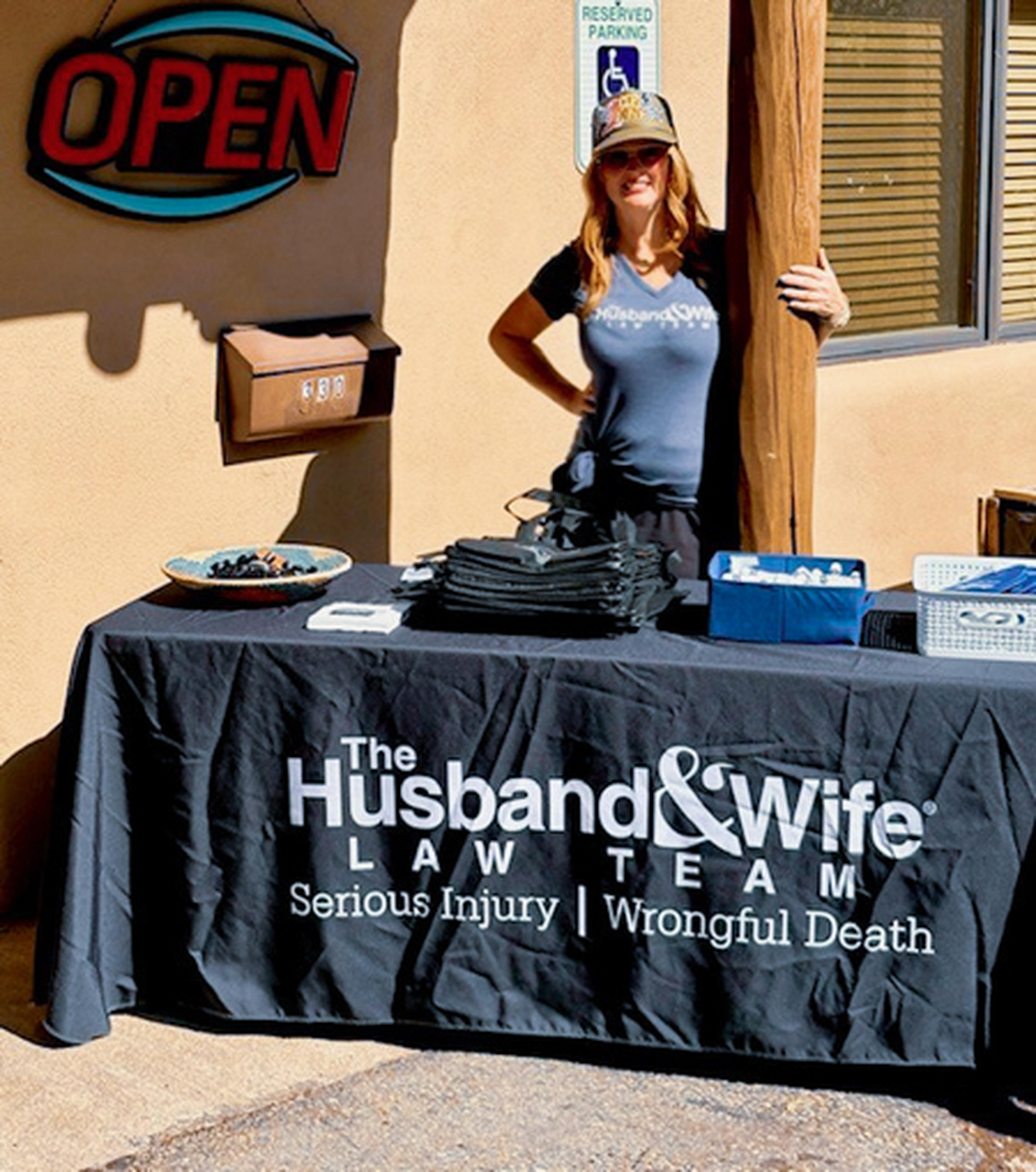 Woman stands behind table branded with The Husband & Wife Law Team