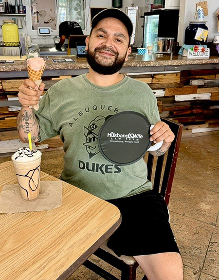 Smiles, sweet treats, and community connection come together as an attendee enjoys ice cream and a Husband & Wife Law Team giveaway at Busy Bee Frozen Custard. A community member enjoys a frozen custard treat at Busy Bee Frozen Custard while showing support for the Husband & Wife Law Team during a local outreach event.